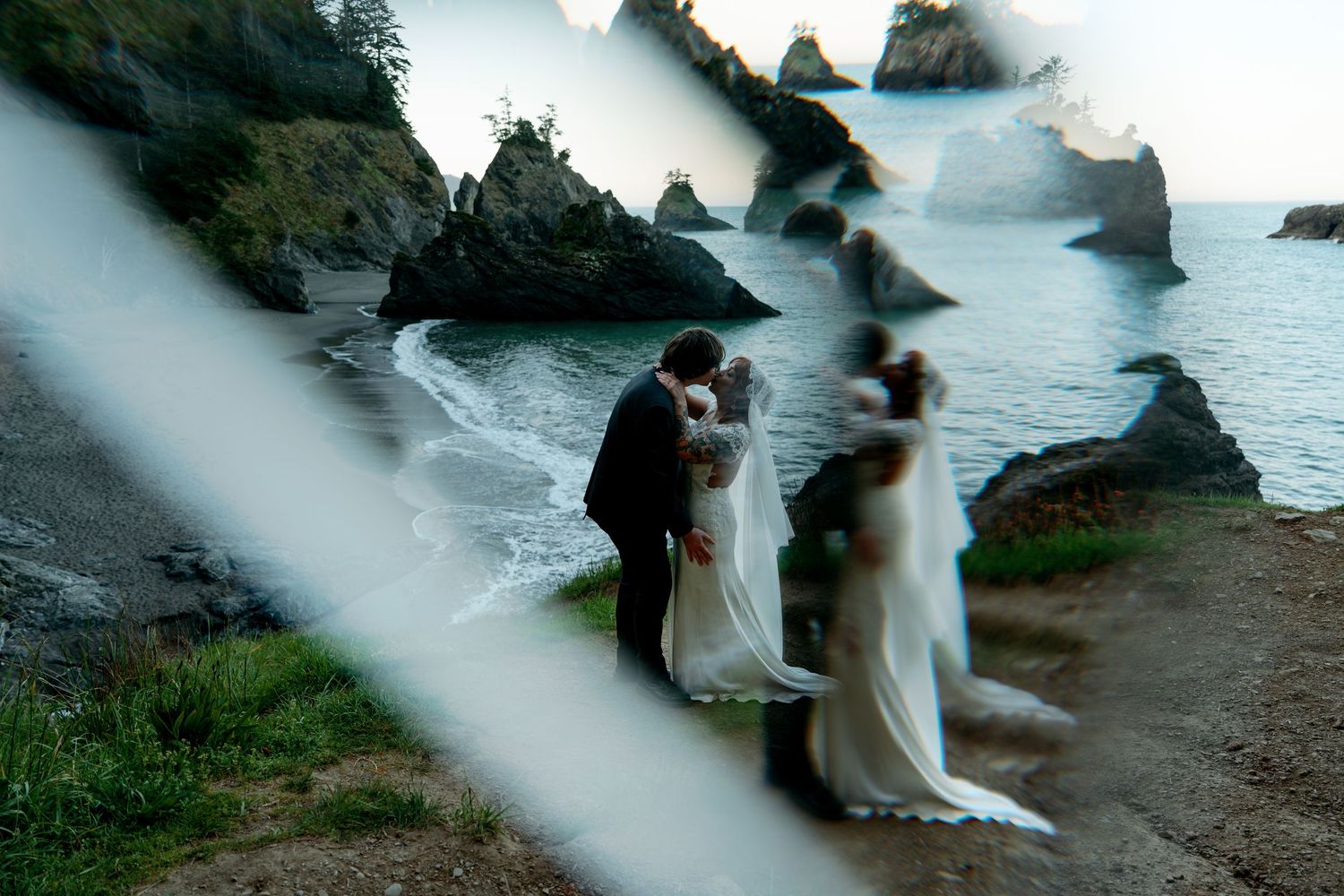 Creative prism lens reflection of bride and groom kissing on a dramatic rocky ocean coastline.