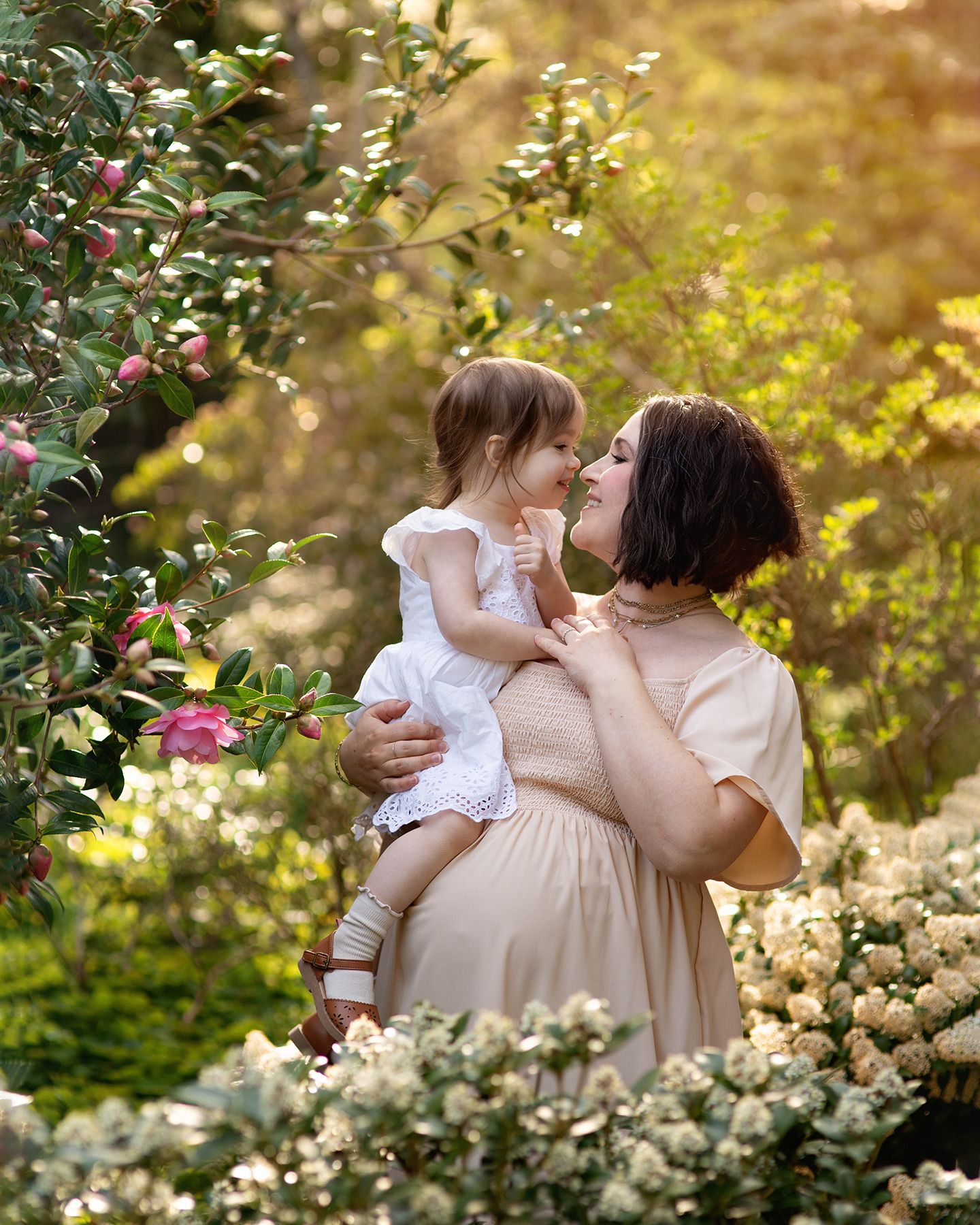 pregnant mother with daughter sharing a moment in a sunlit spring garden, Victoria BC maternity session