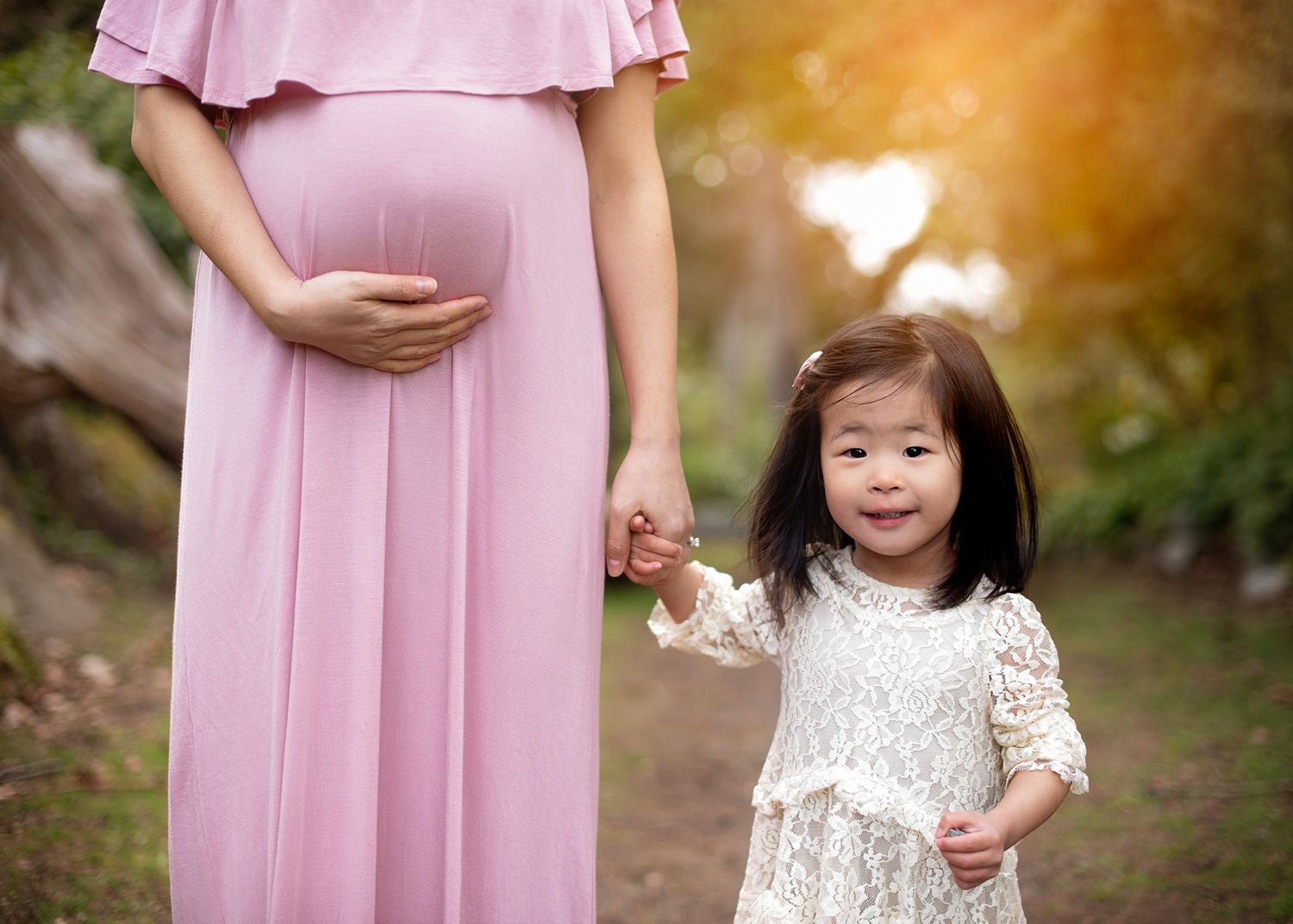 mother-to-be with child walking hand and hand in a sunlit spring garden, Victoria BC