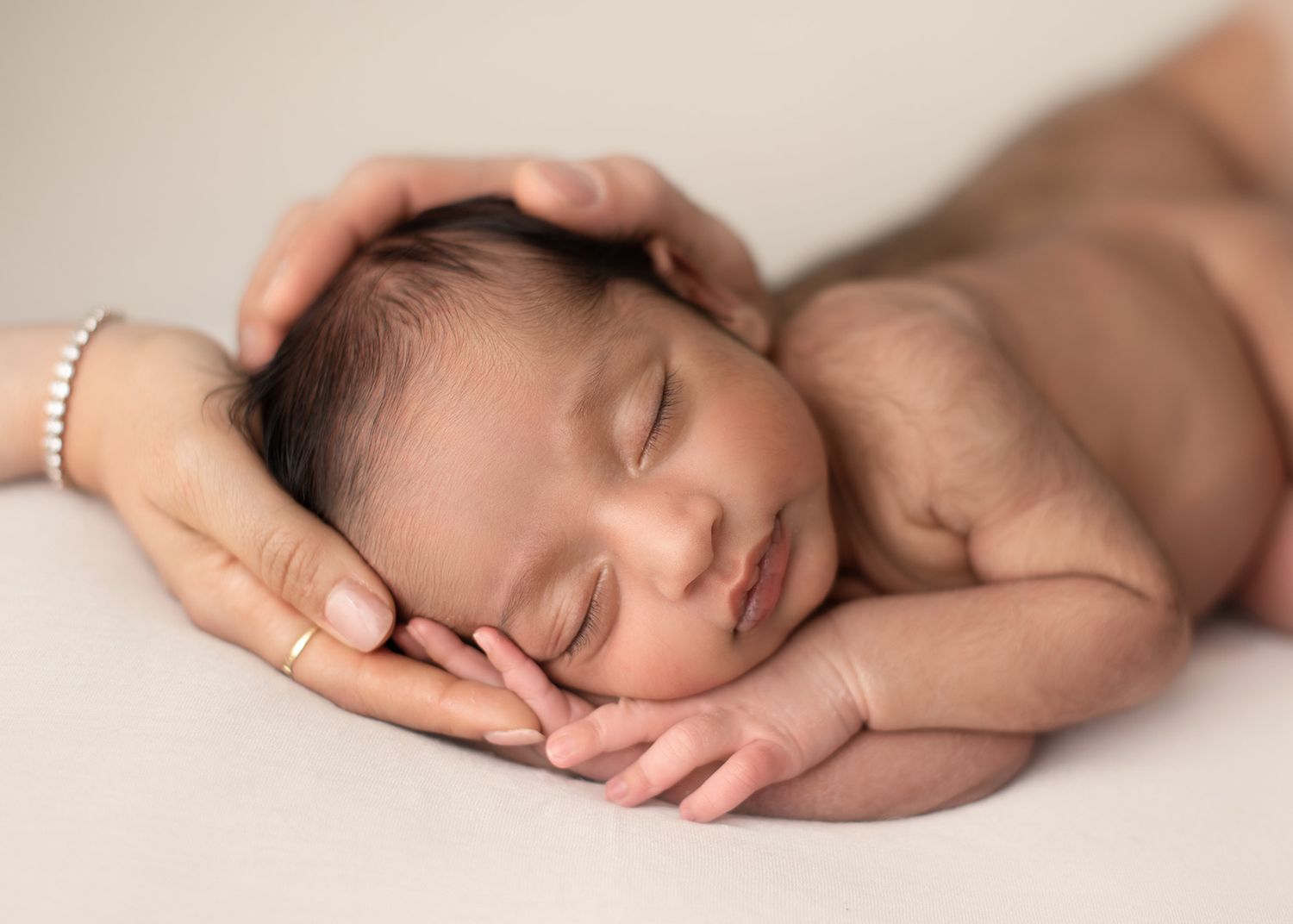 sleeping newborn baby held gently in parents hands, intimate studio portrait, Victoria BC