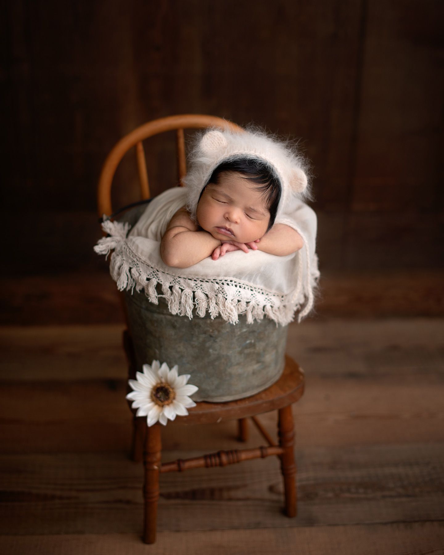 baby posed in a bucket on a vintage chair wearing a bear bonnet, cozy studio setup, Victoria BC newborn photography
