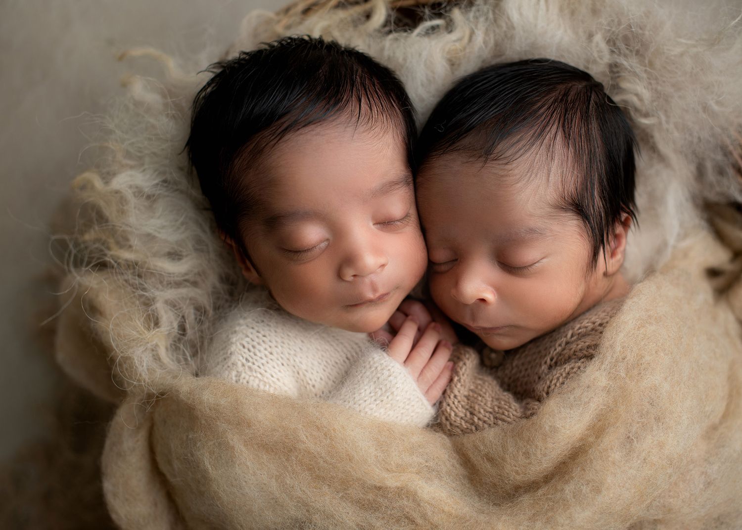 twin newborn babies lying together holding hands in soft neutral layers, cozy studio setup, Victoria BC newborn photography