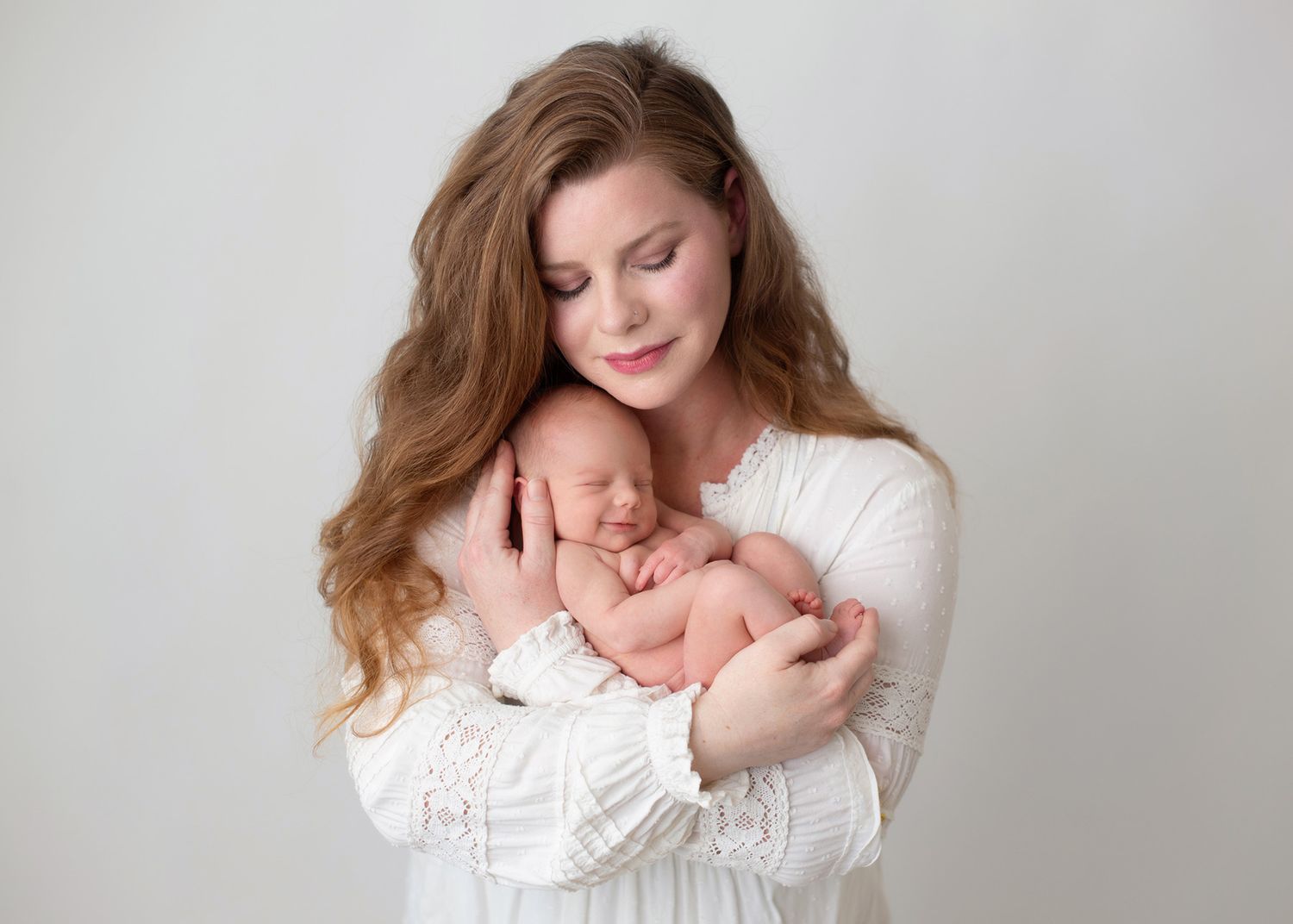 A peaceful moment of a mother gently holding her newborn baby in her arms, Victoria newborn family photographer