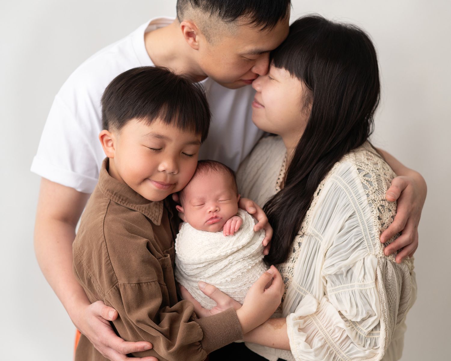 Parents and sibling loving embracing sleeping newborn baby, soft studio portrait, Victoria BC