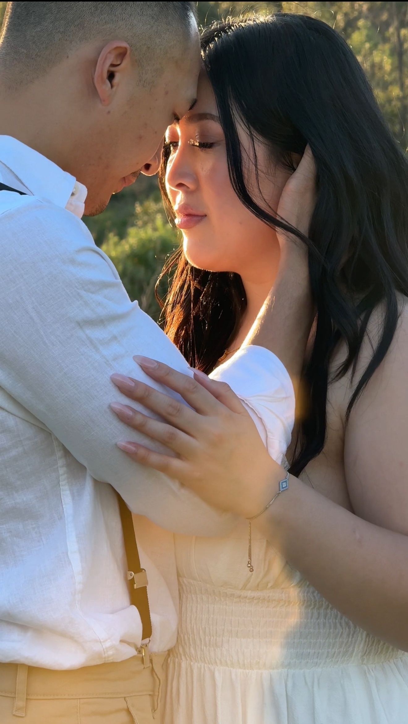 A tender romantic moment captured in warm sunlight during an outdoor photoshoot.