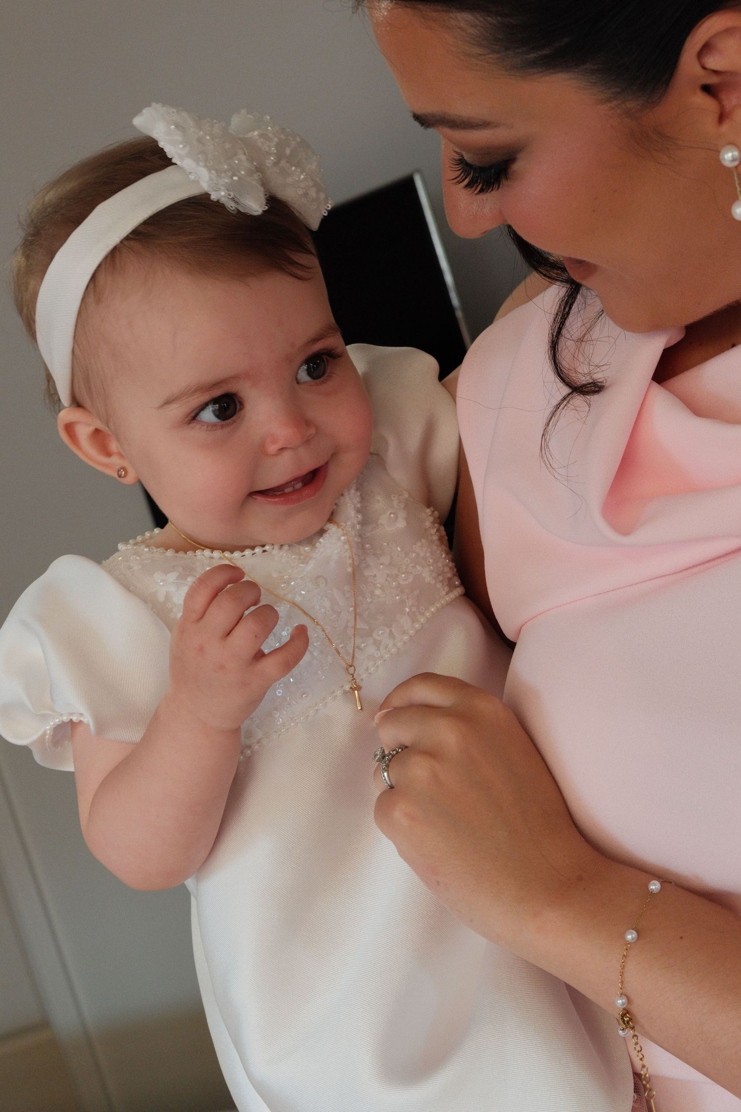 A tender moment captured between a mother and baby in white christening attire.