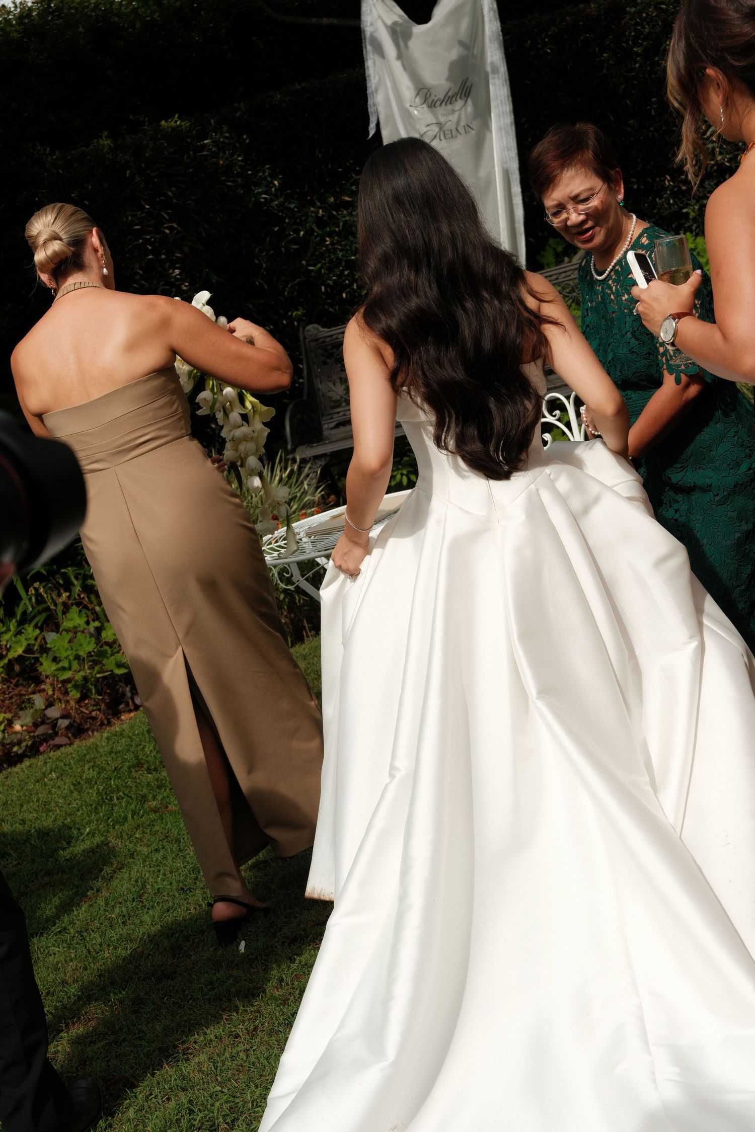 Wedding party gathered outdoors with bride in flowing white dress and attendants in earth-toned gowns.