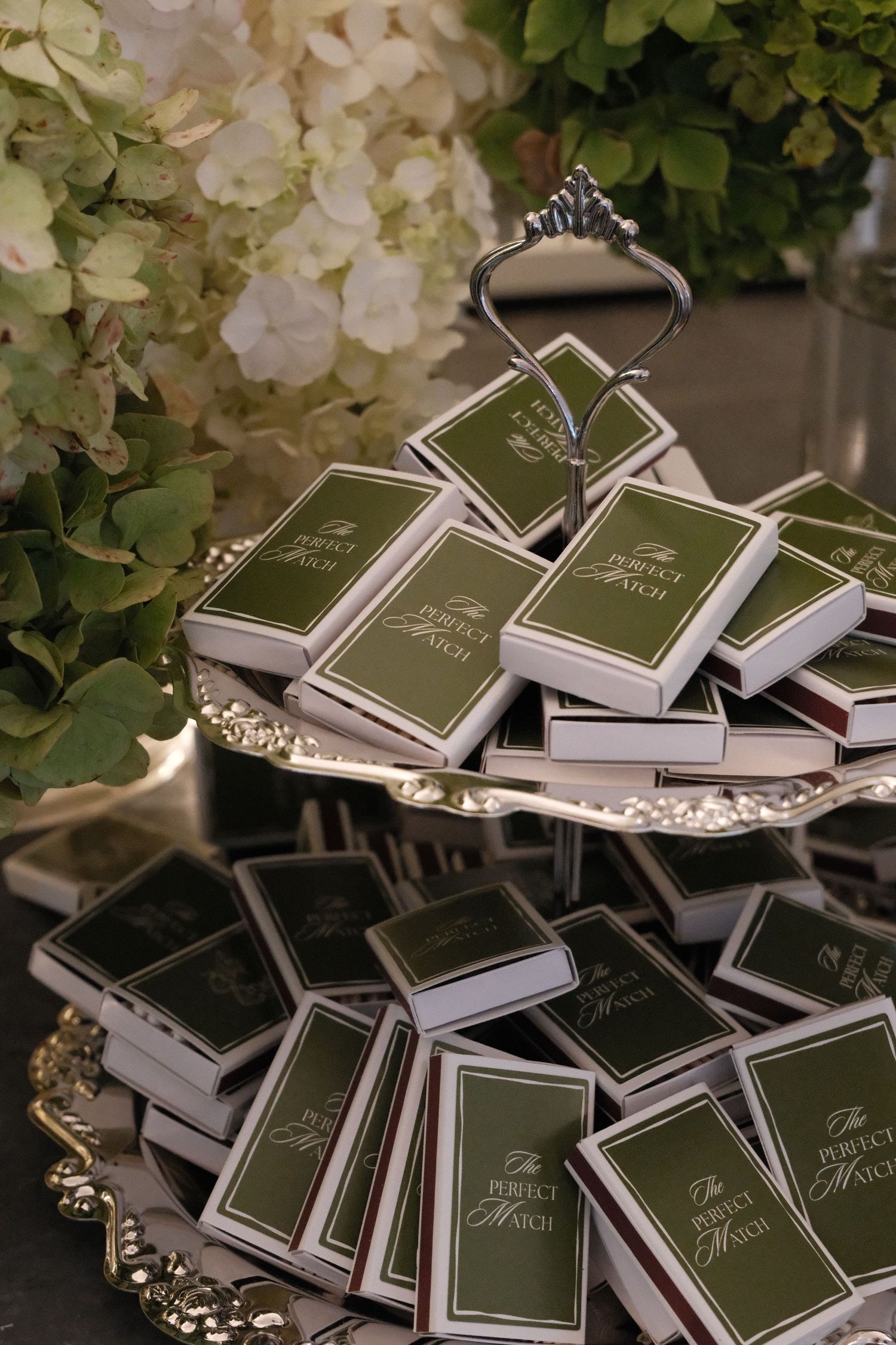 Elegant wedding favors displayed with green books and decorative tiaras arranged on a table.