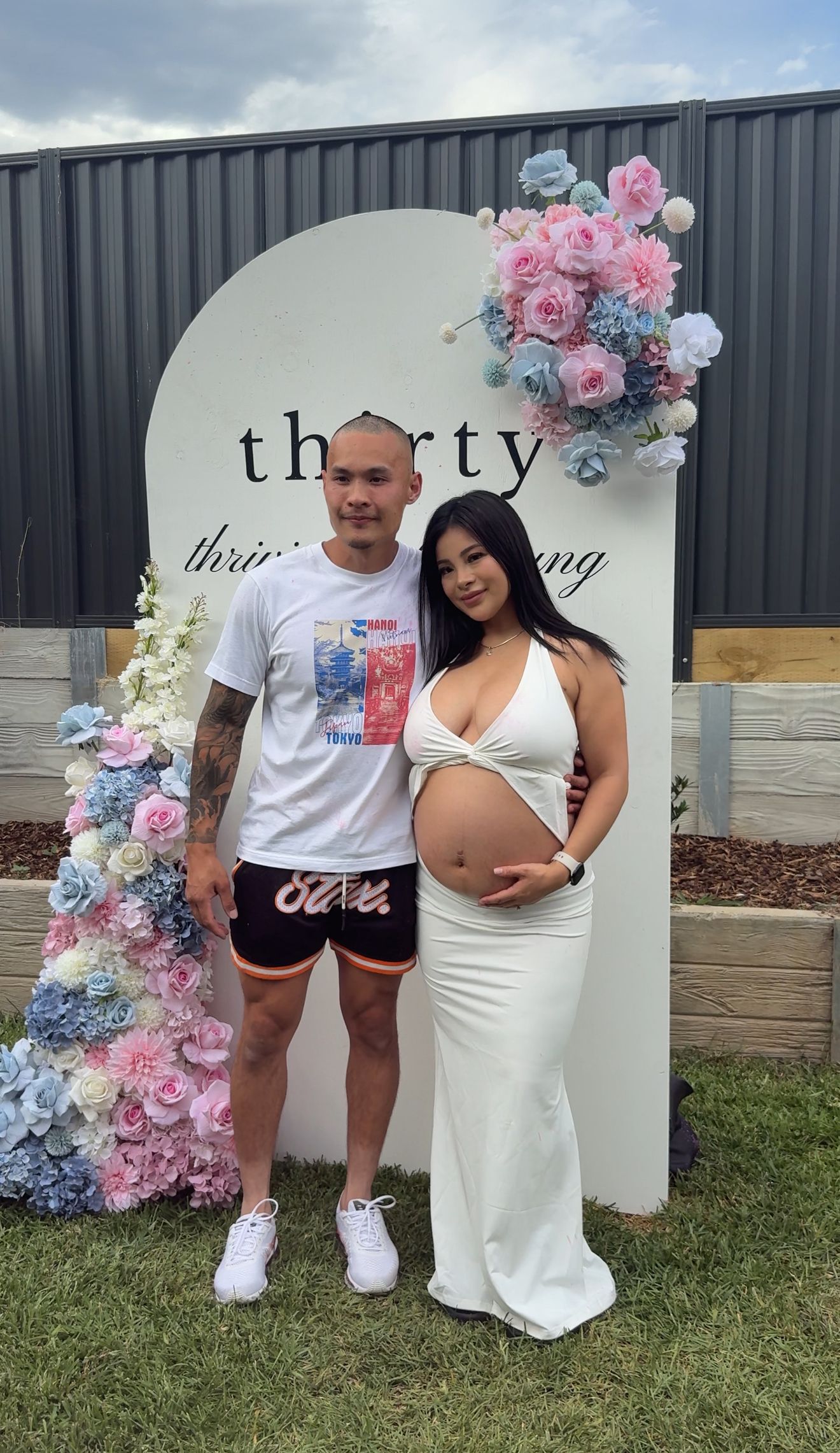 Maternity celebration with floral backdrop and casual outfits.