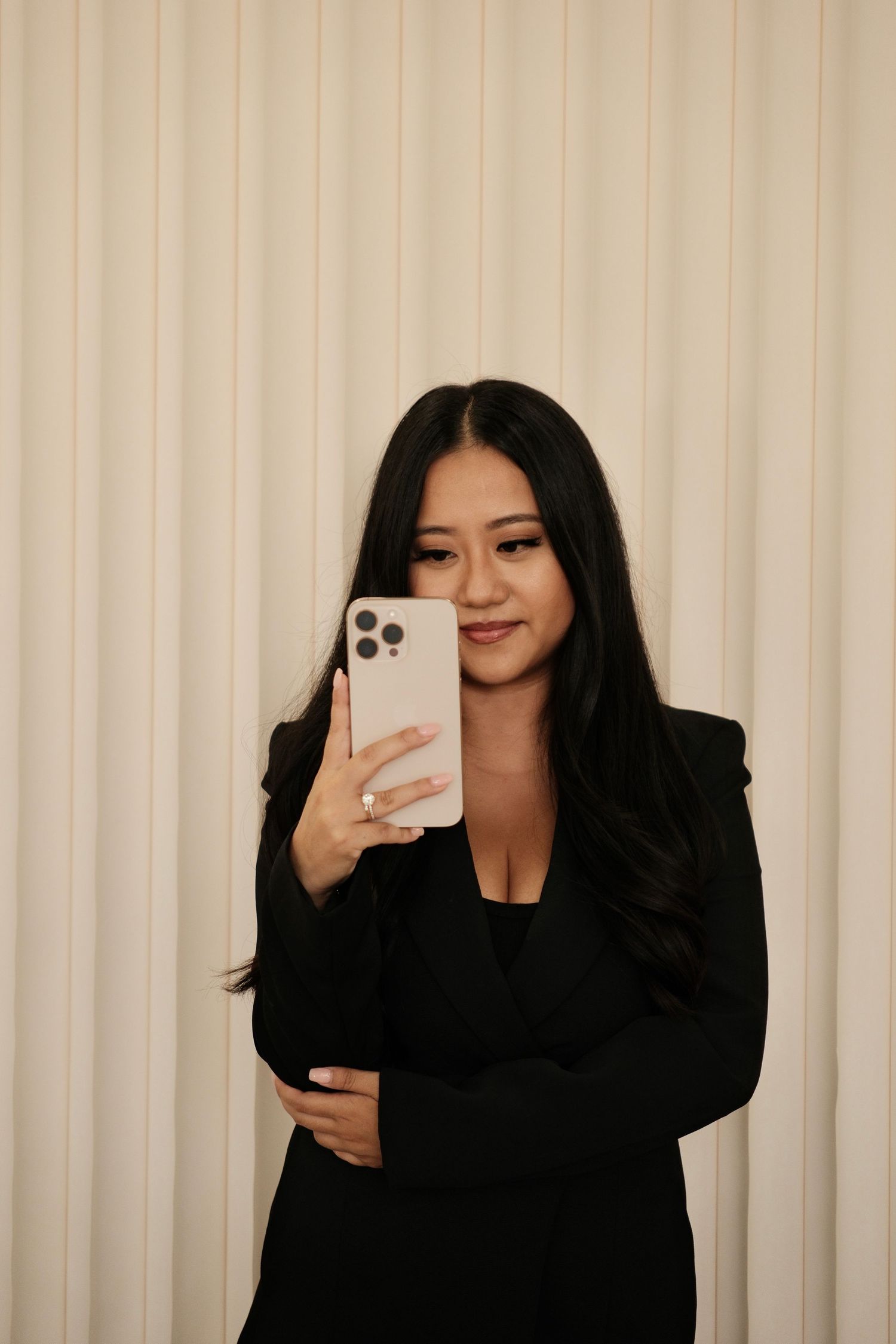 Woman in black outfit taking mirror selfies with smartphone.