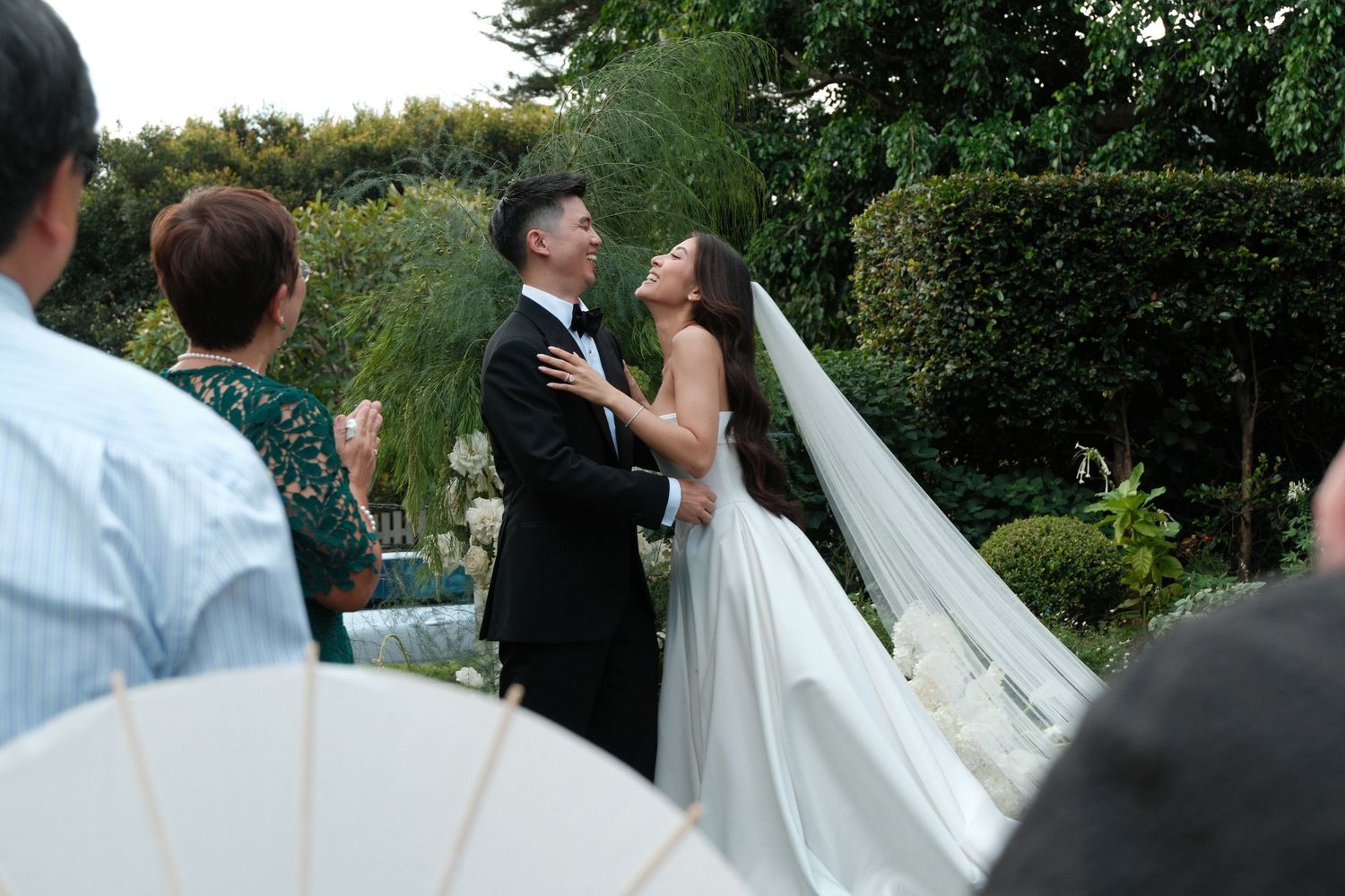 A wedding celebration outdoors with people dancing and celebrating in a garden setting.