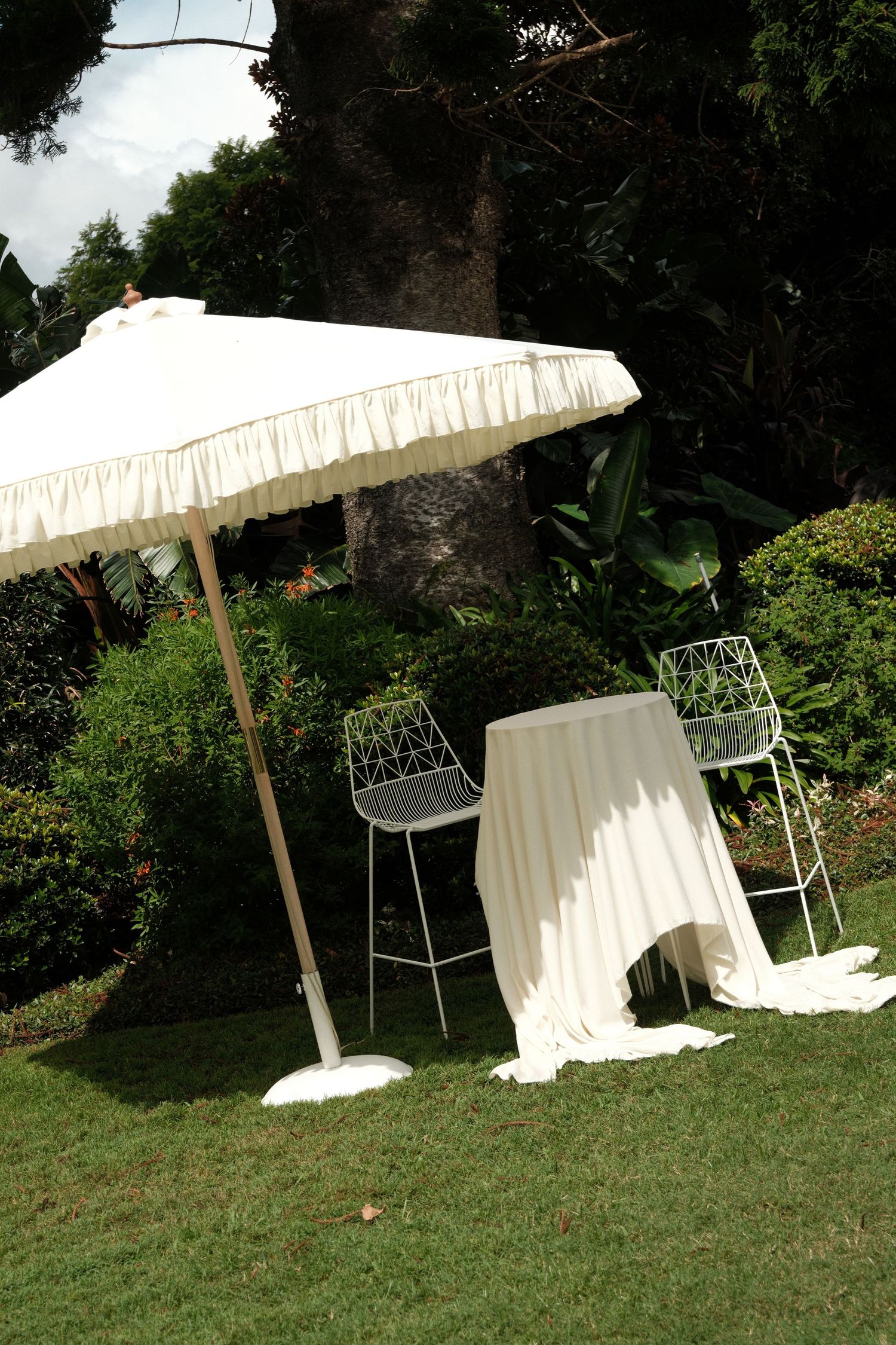 Elegant white parasols and chairs create a romantic outdoor wedding seating area.