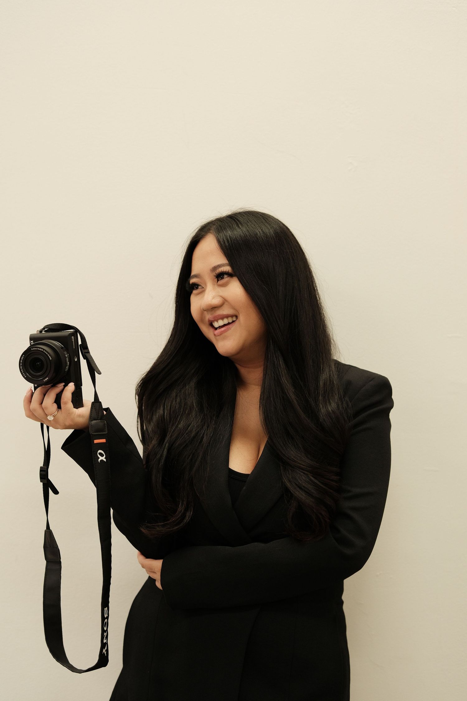 Woman in black holding professional camera in various poses.