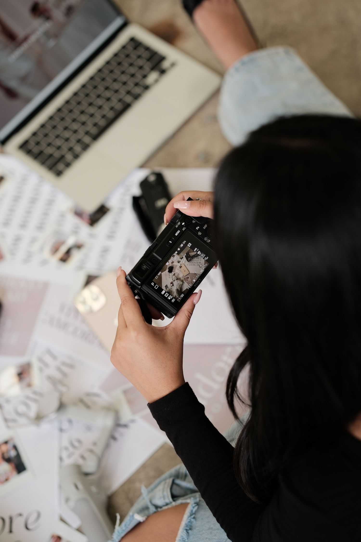 Overhead view of person working with phone and laptop surrounded by papers.