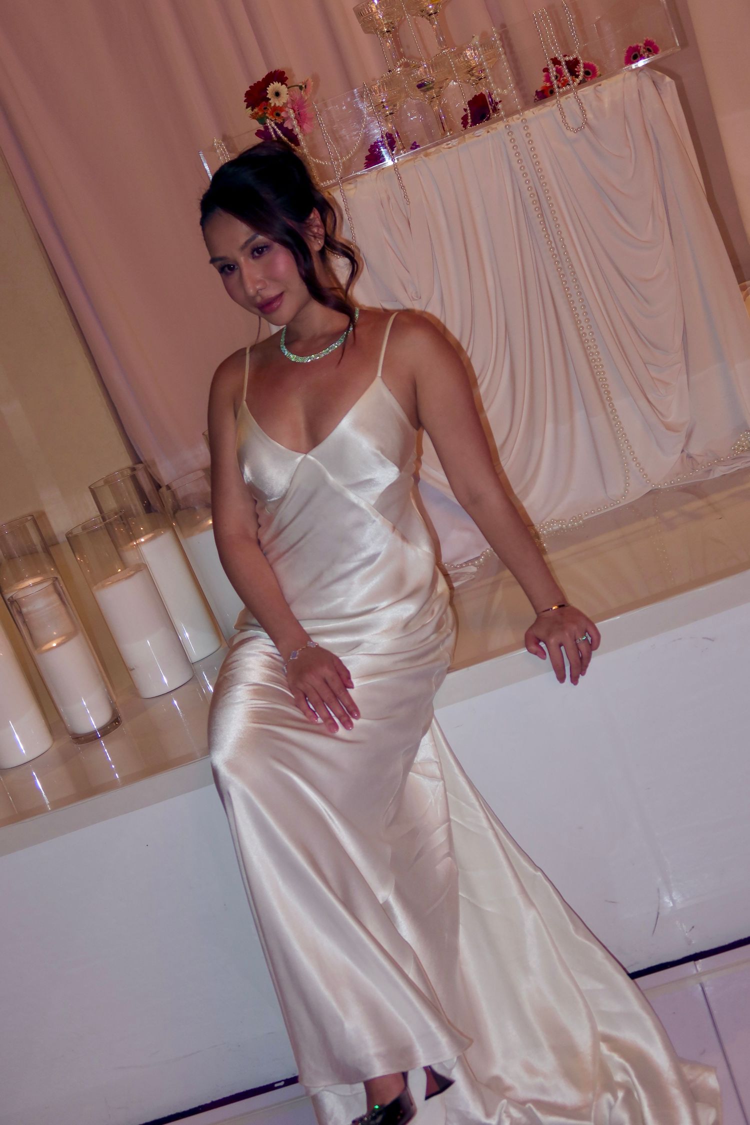 A series of photos showing someone wearing a sleek white satin dress in an elegant indoor setting.