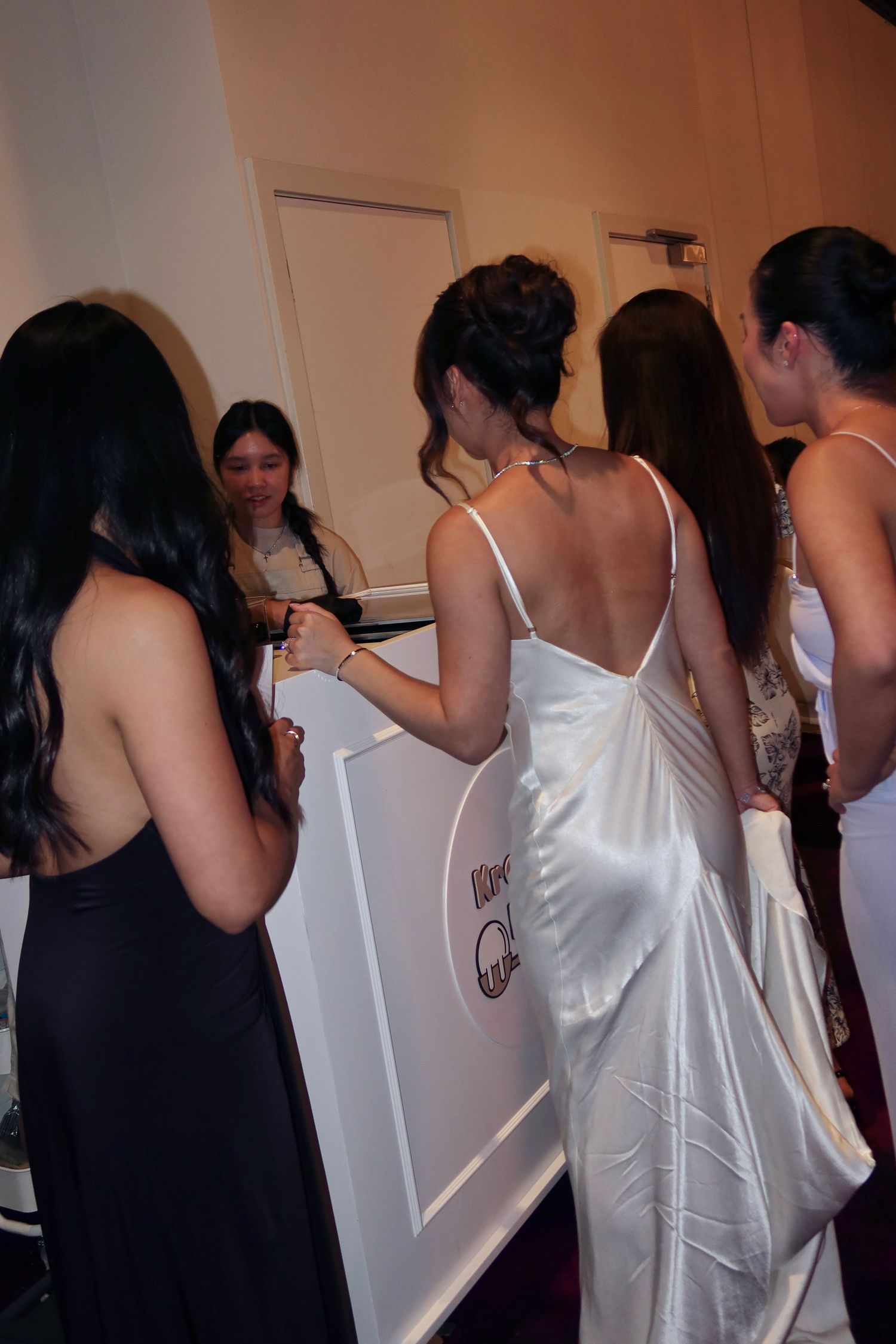 A group of people in formal attire gathered around signing what appears to be a guest book at an event.