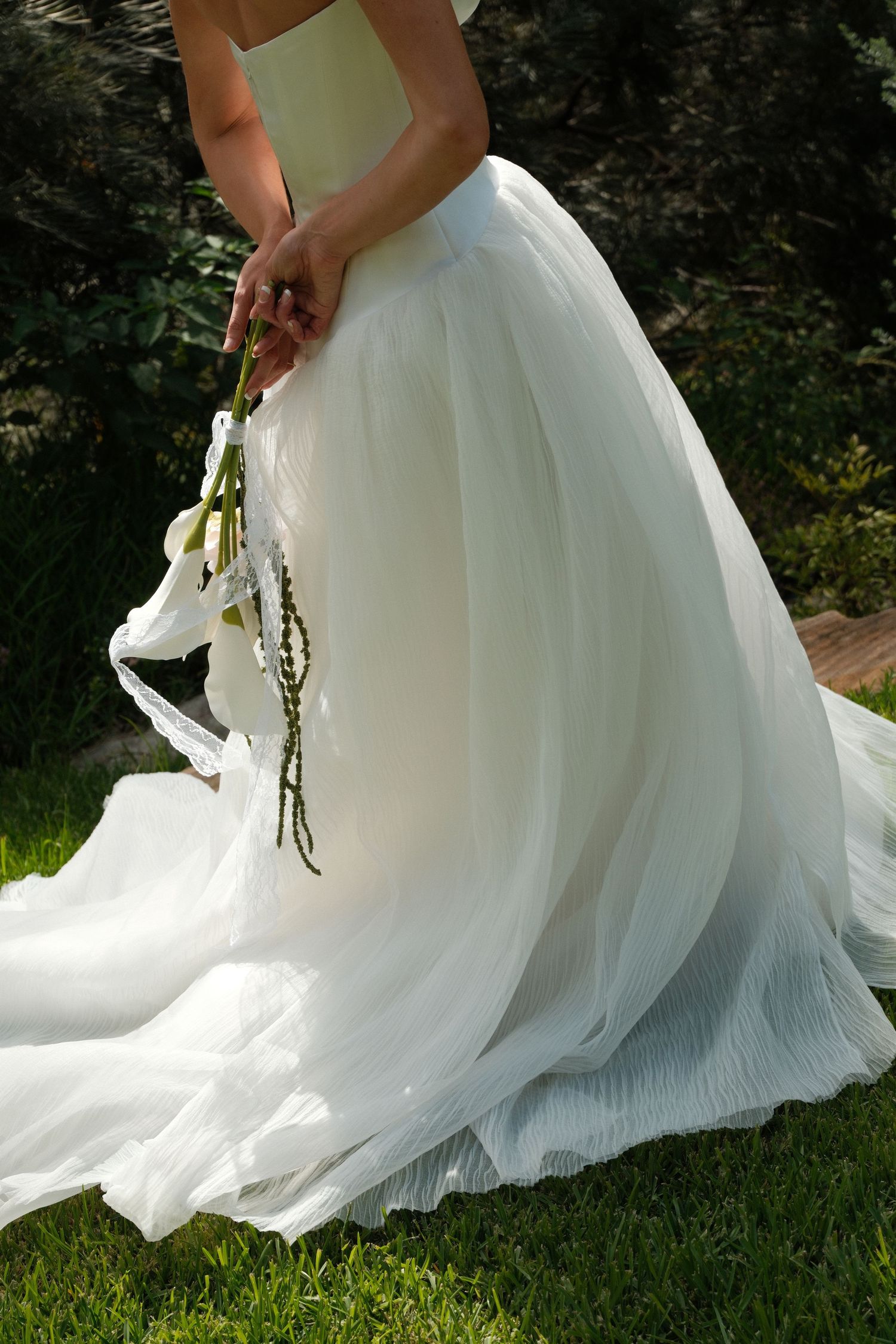 Flowing white wedding dress skirt twirling gracefully on green grass in a series of romantic outdoor shots.