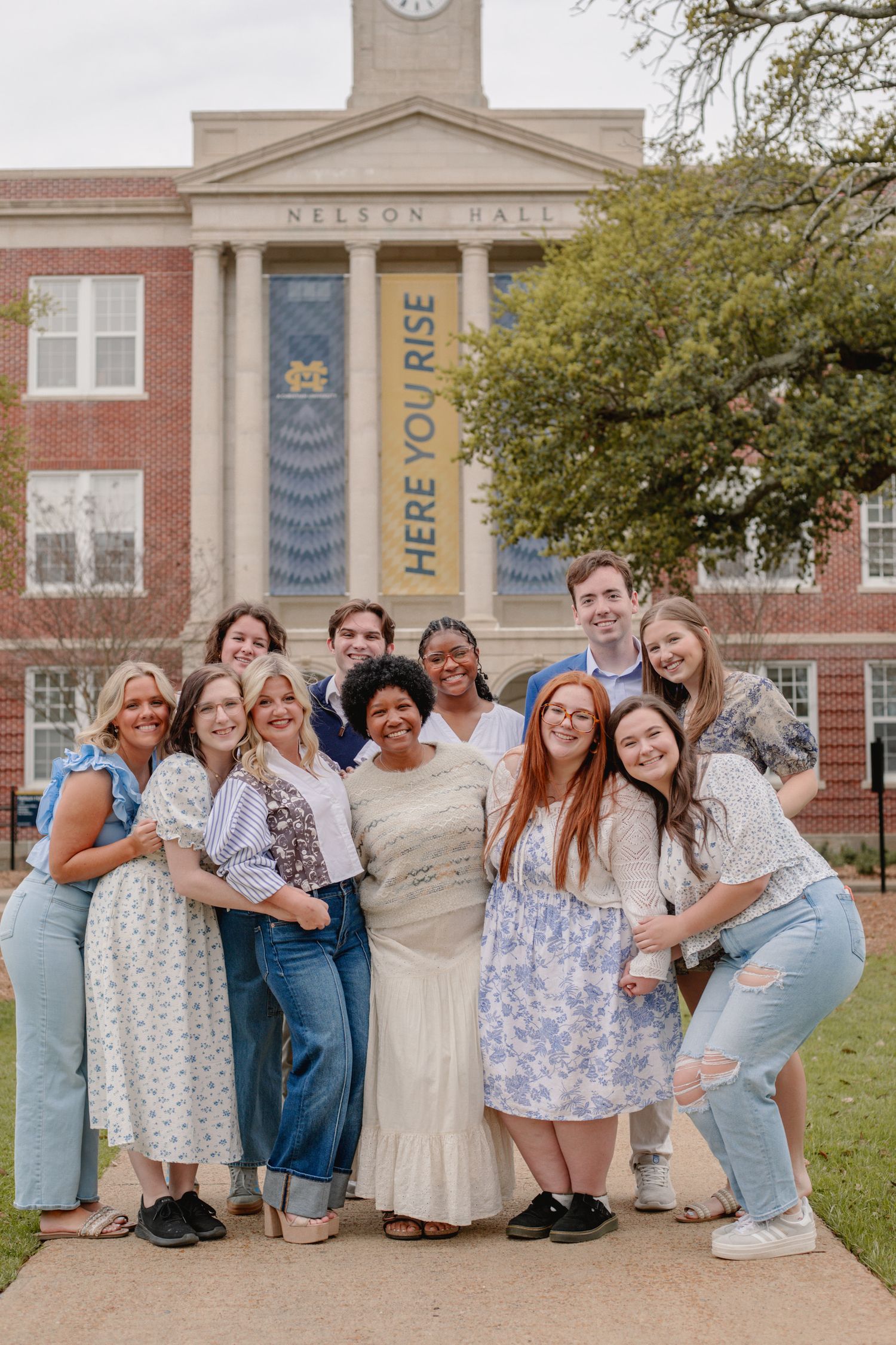 Group photo of students posing together outside a brick university building.