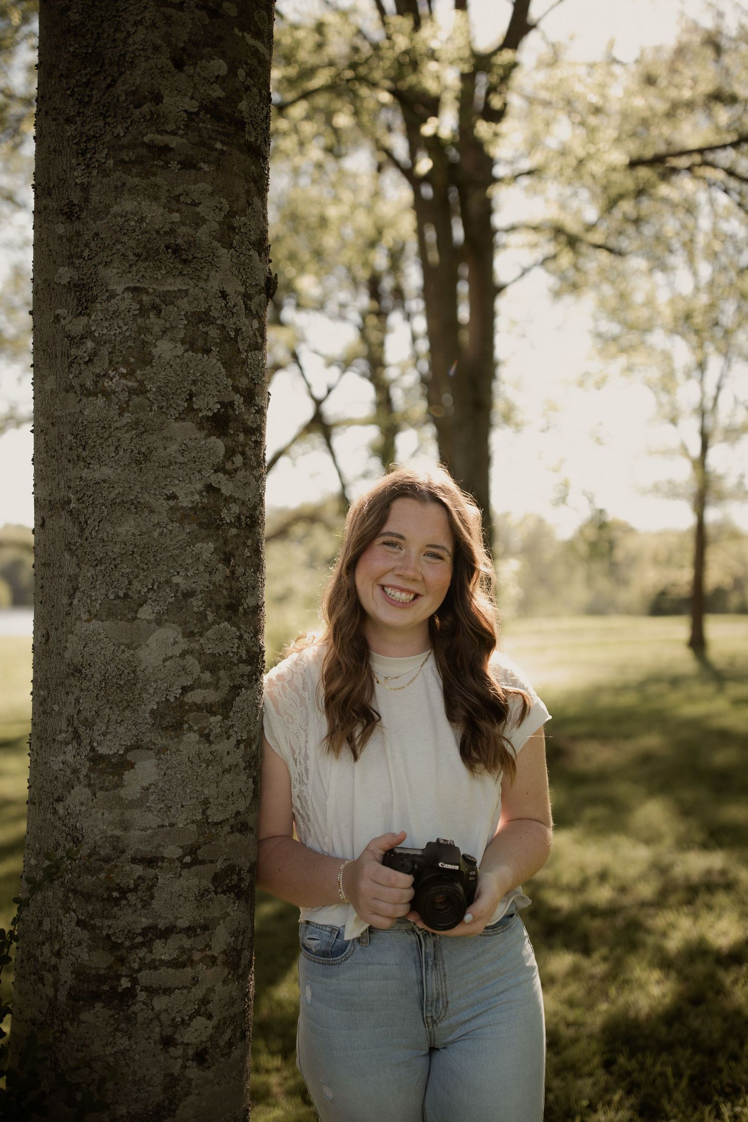 Sunlit portrait sequence between tree trunks in a natural outdoor setting.