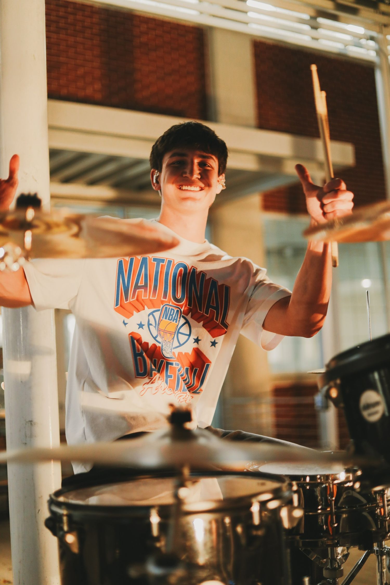 A drummer performing energetically on stage wearing a National championship t-shirt.