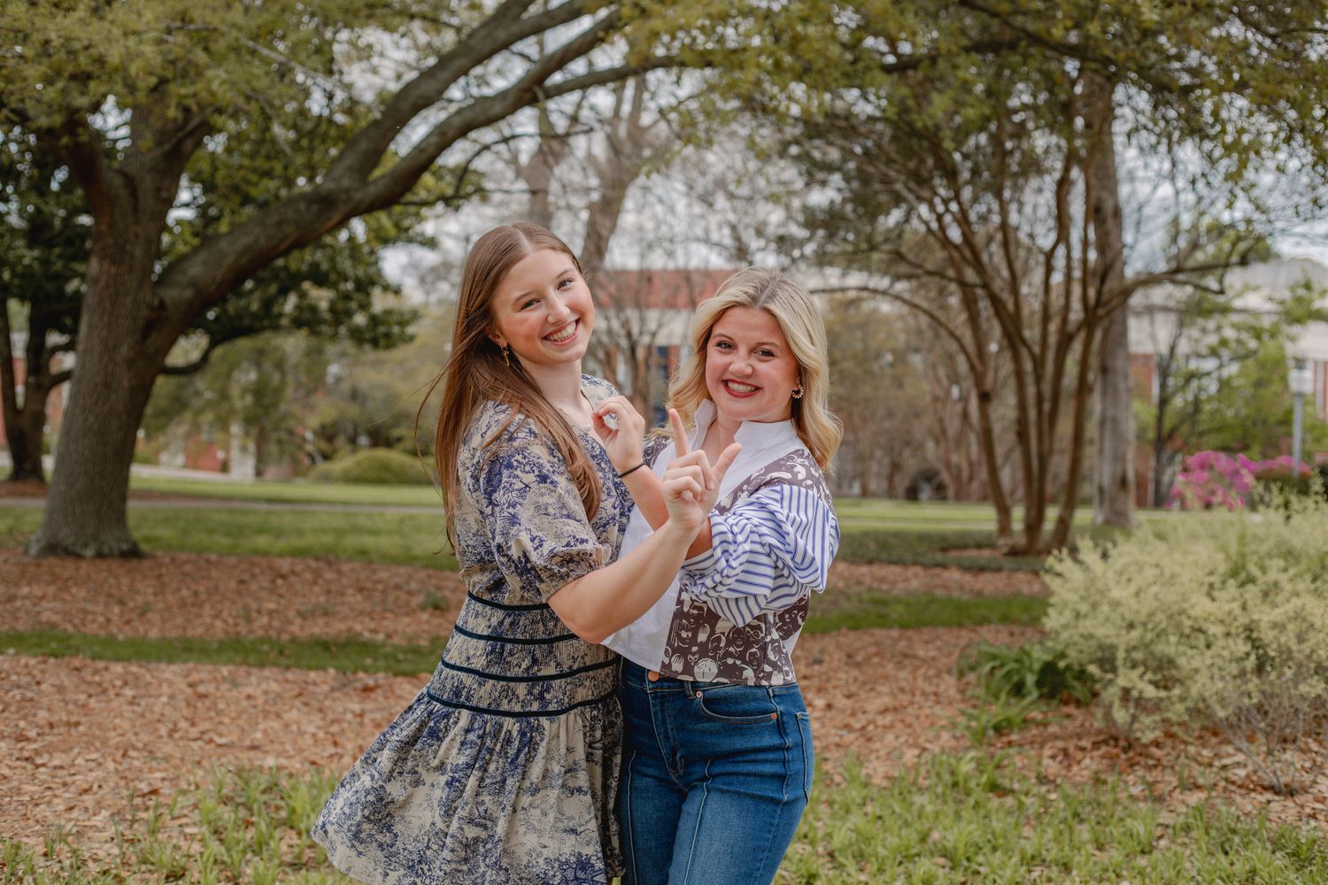 Two friends holding a small dog while posing outdoors.