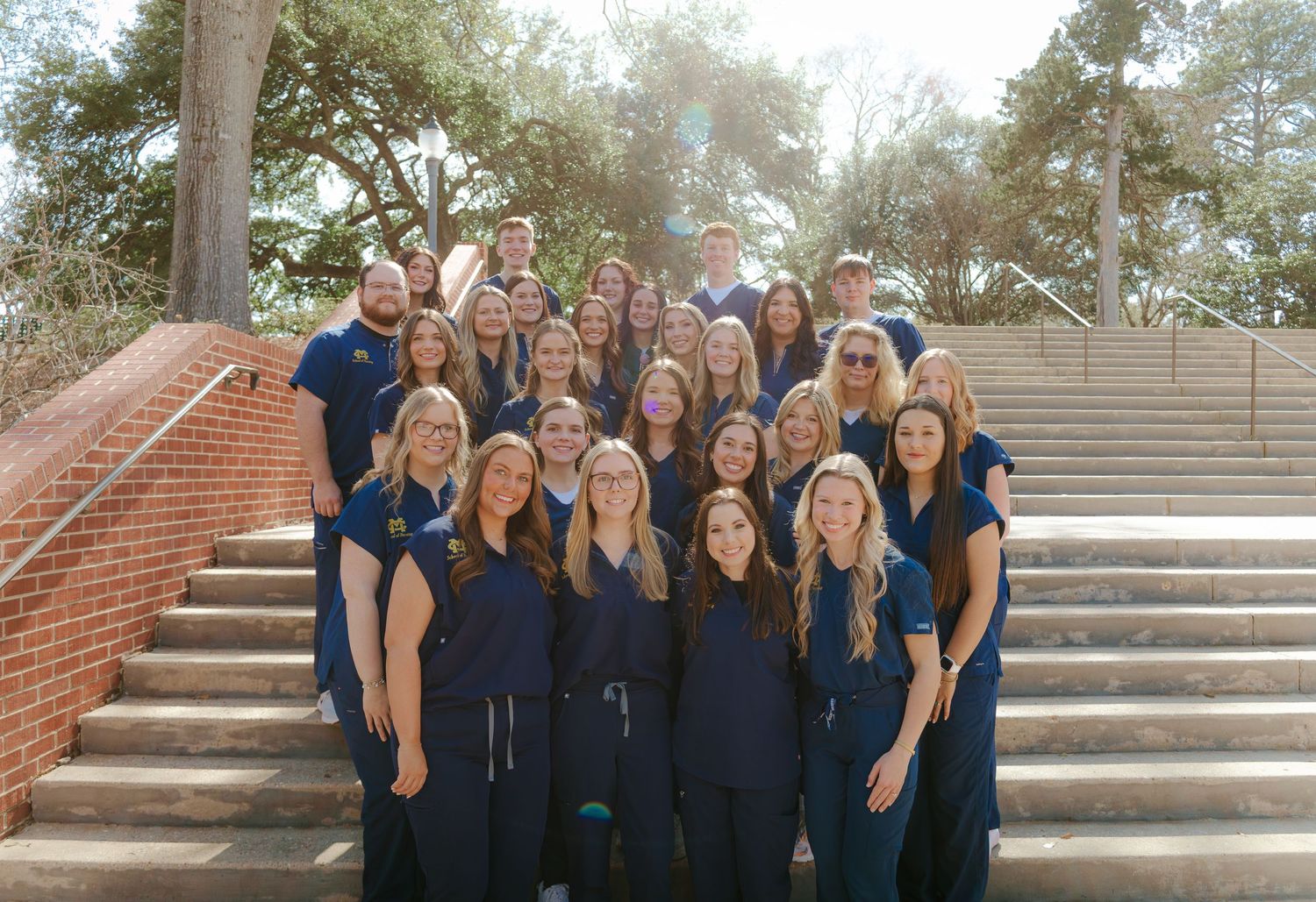 Row of students in matching navy outfits posing on outdoor stone steps.