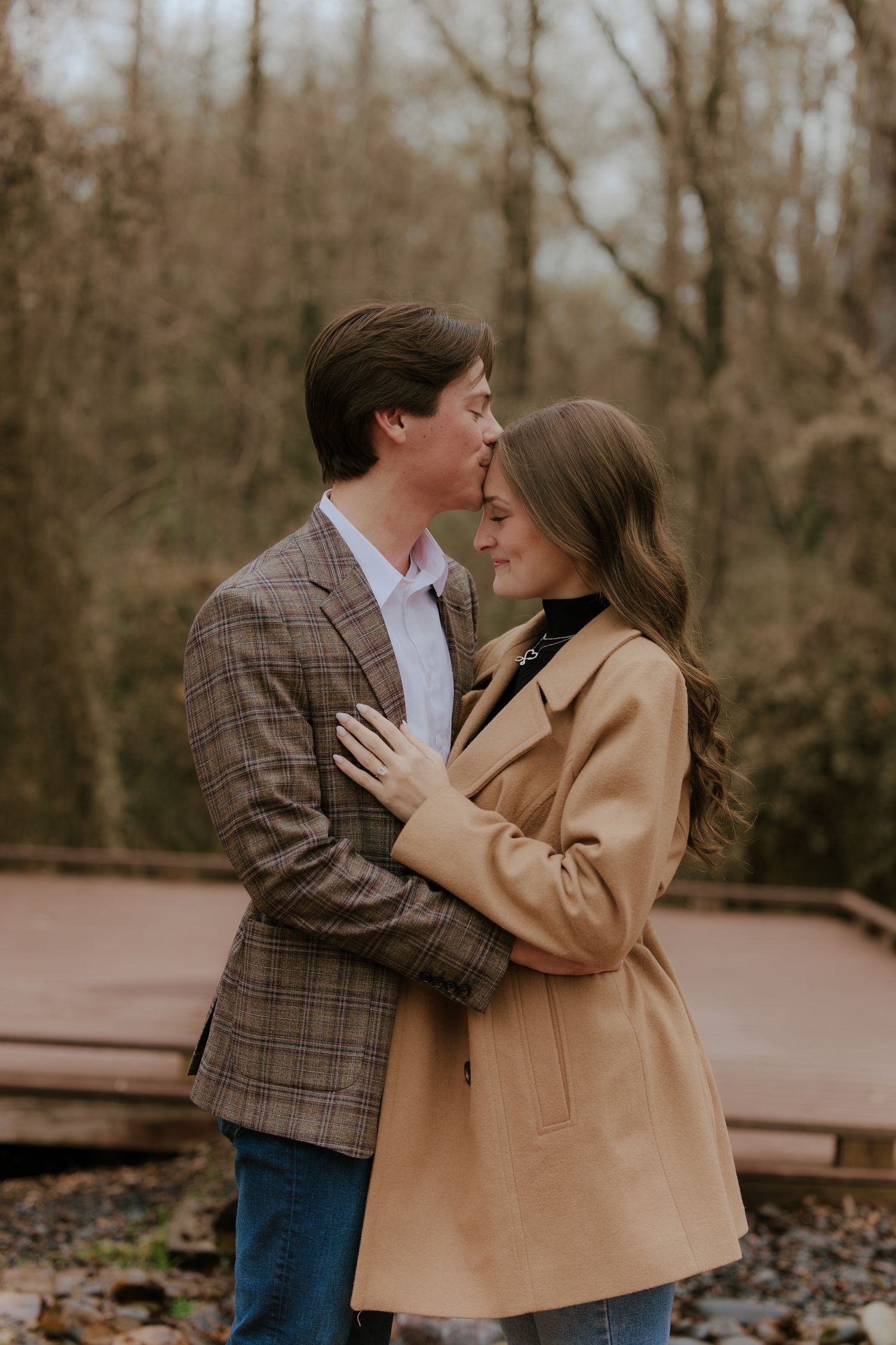Couple sharing an intimate moment outdoors wearing casual fall attire.