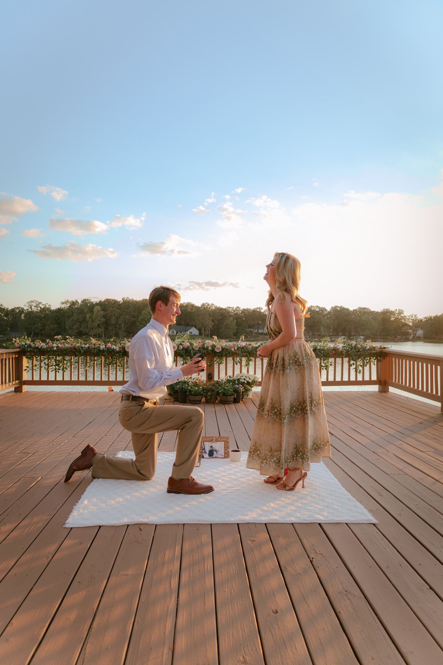A marriage proposal sequence unfolds on a wooden deck overlooking a waterfront at sunset.