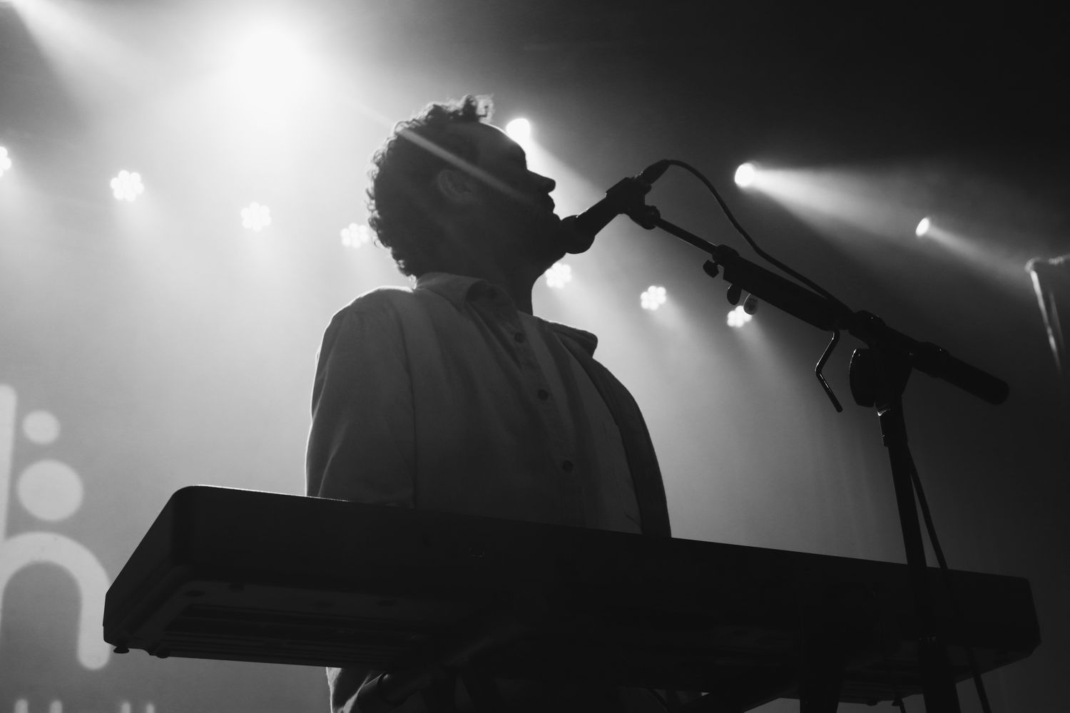 Dramatic black and white silhouettes of performers on stage with spotlights.