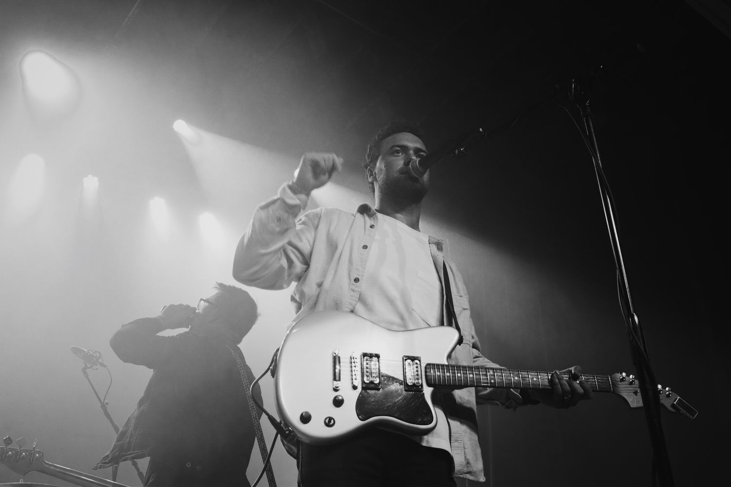 Black and white silhouettes of musicians performing on stage with dramatic lighting.