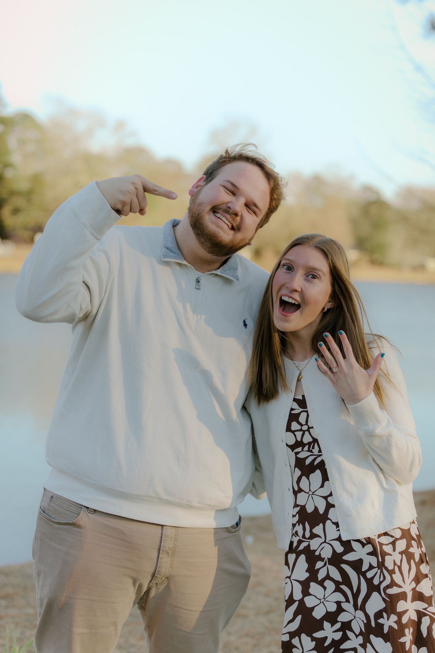 A joyful couple in matching white sweaters share candid laughter during an outdoor photo session.