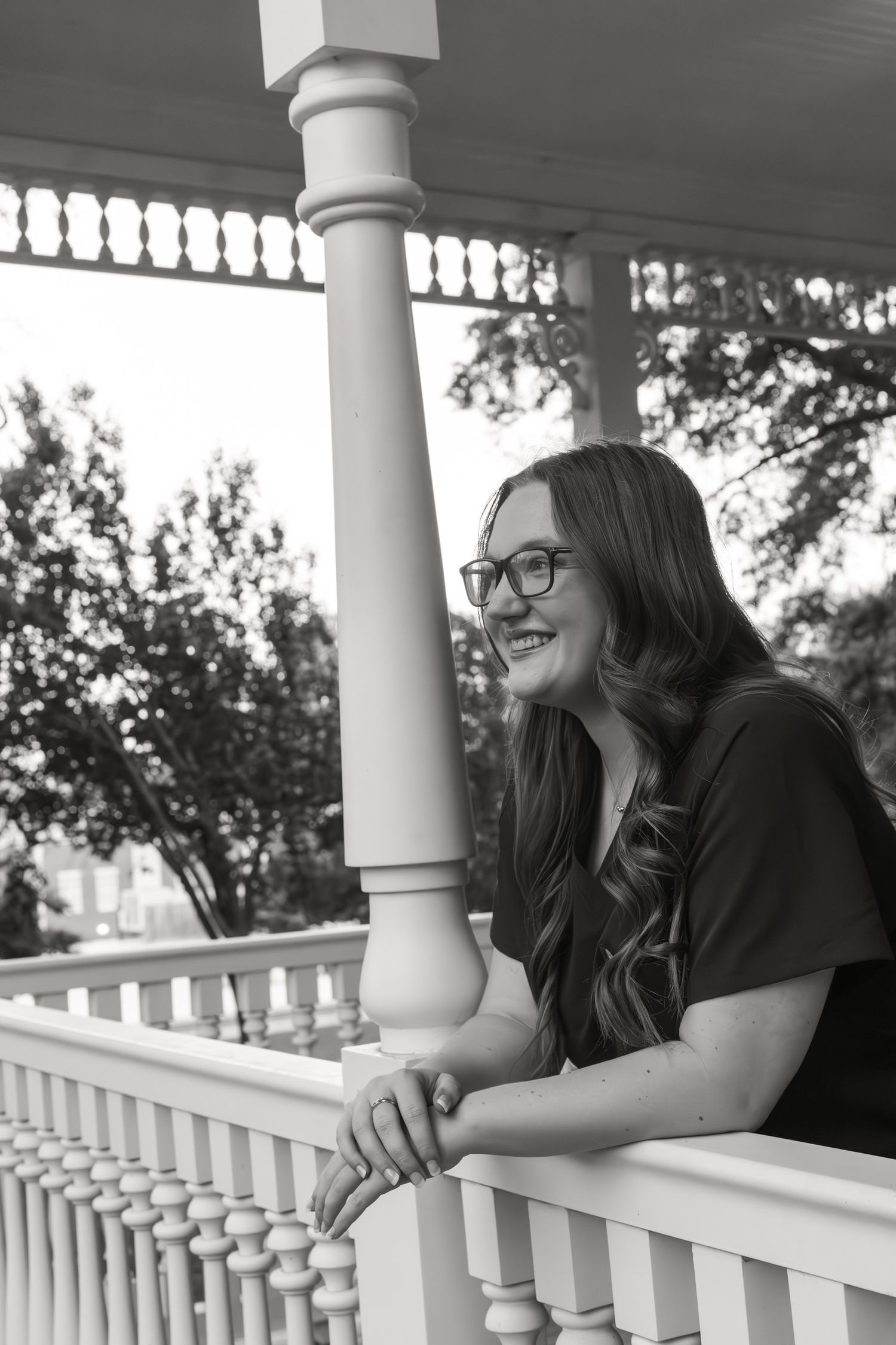 Two friends sharing laughter while leaning on a white porch railing.