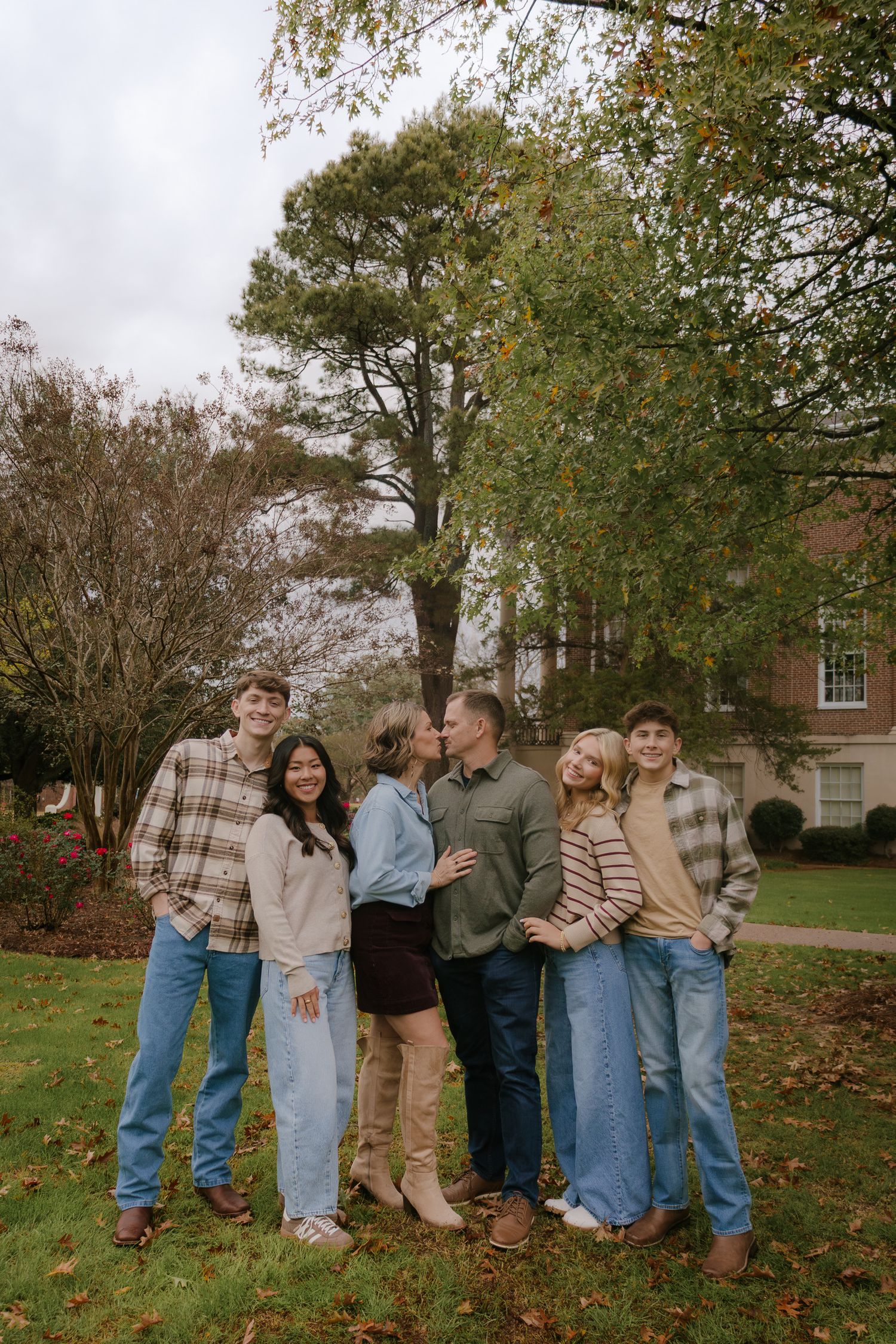 A casual group photo on an autumn lawn with fallen leaves and trees in the background.
