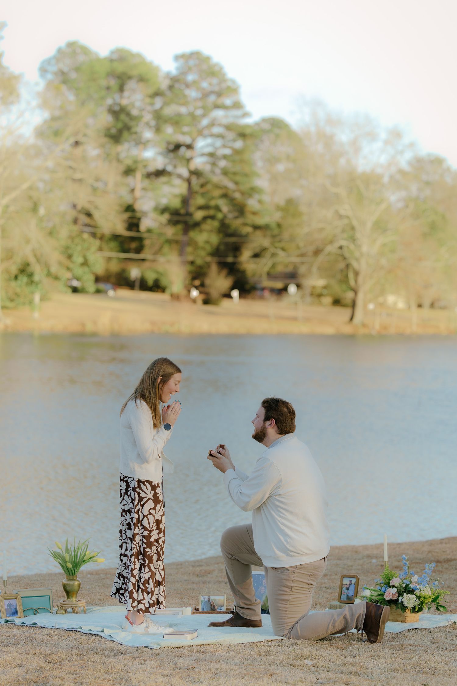 Couple enjoying a romantic picnic by the lake with blankets and refreshments.