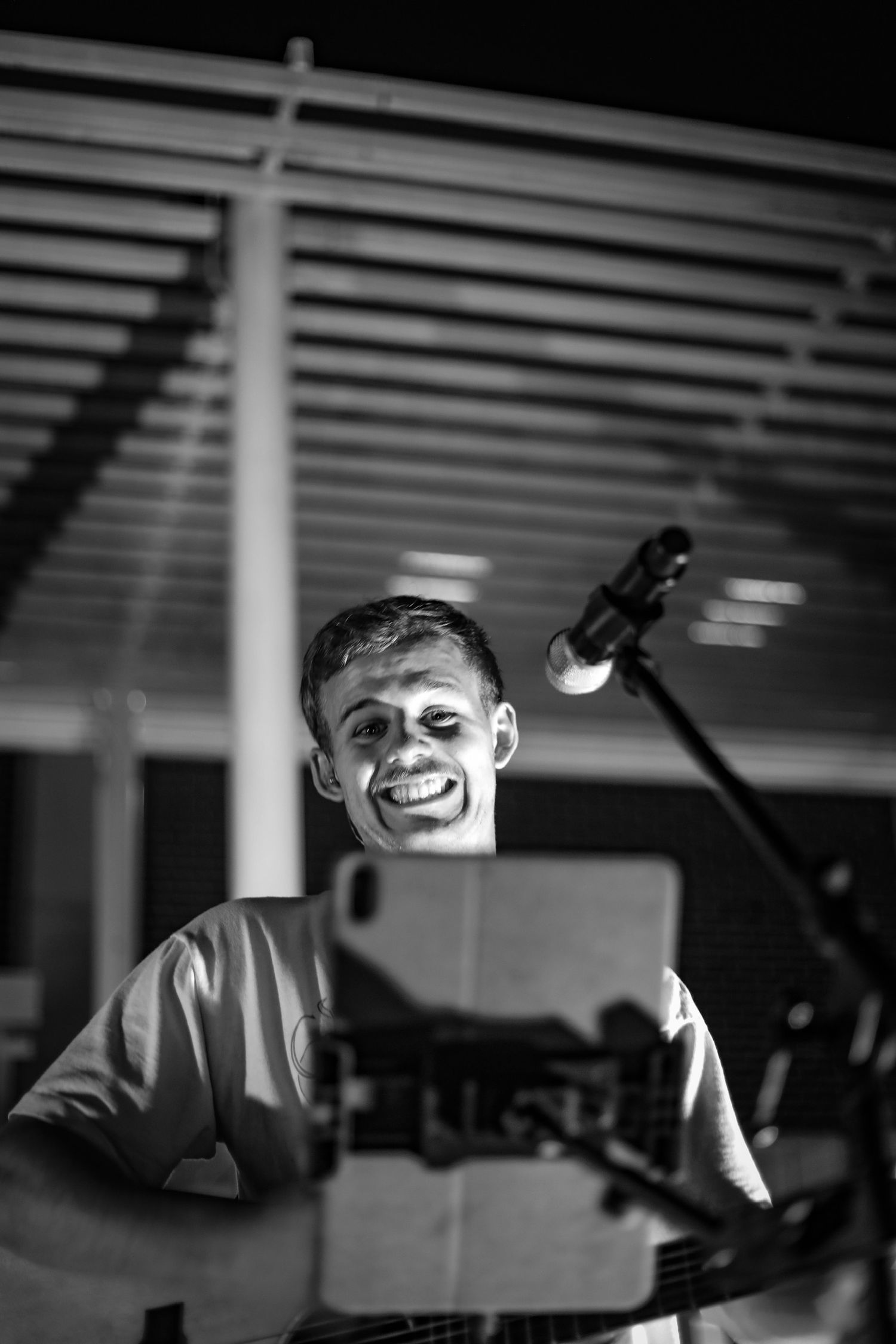Musician performing with a keyboard on stage in black and white lighting.