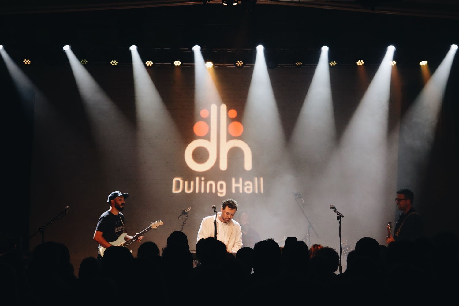 Stage lighting illuminates Dulina Hall logo during live performance.