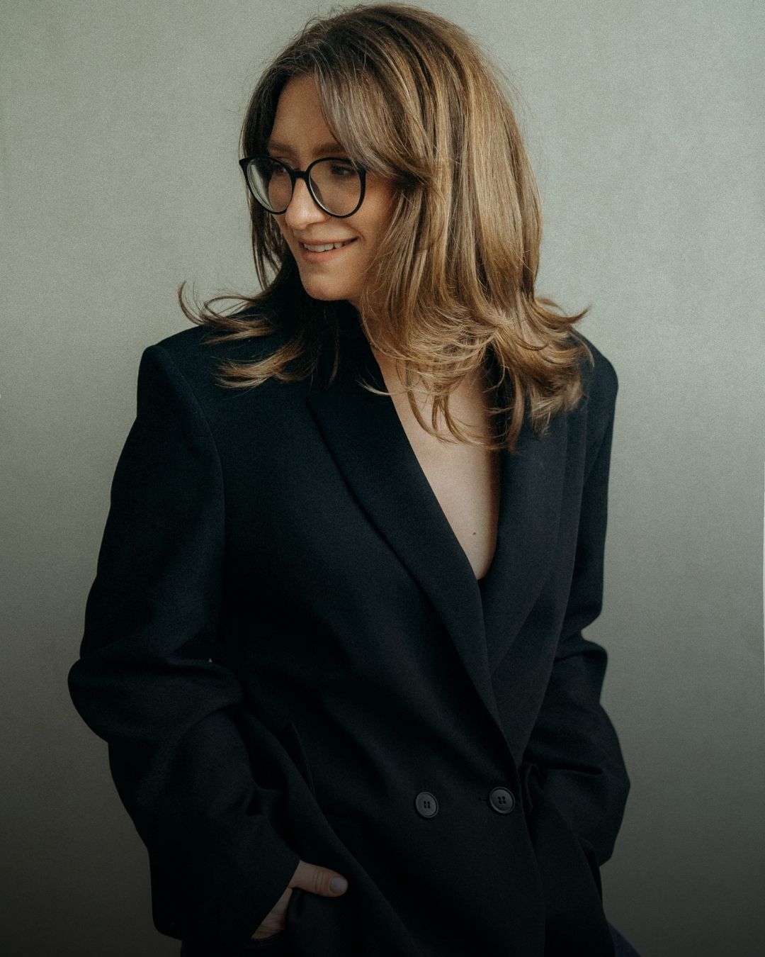 Professional portrait series showing person with glasses in black blazer against neutral background from different angles.