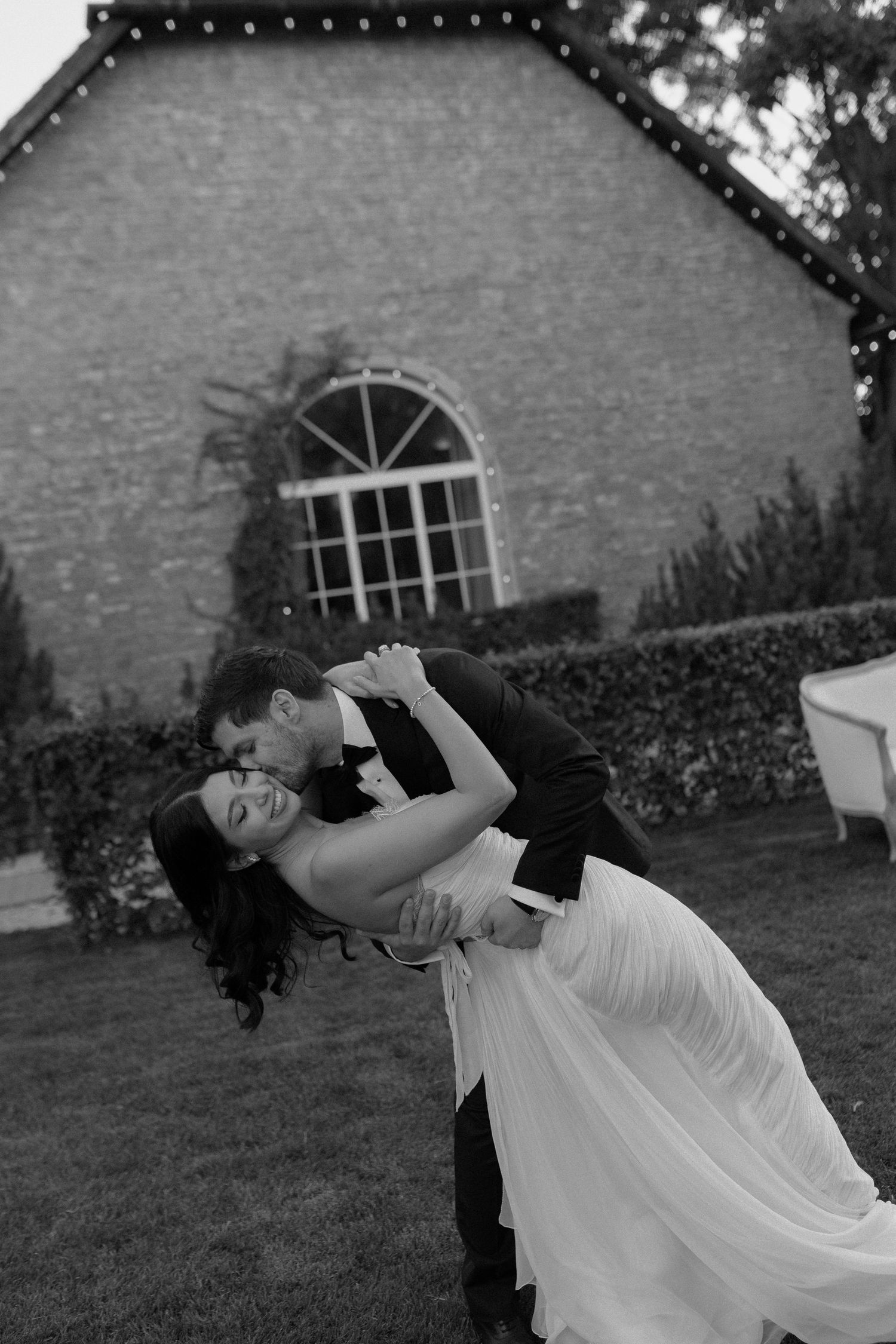 A sequence of black and white photos shows a person in white clothing reclining and stretching backwards on a lawn.