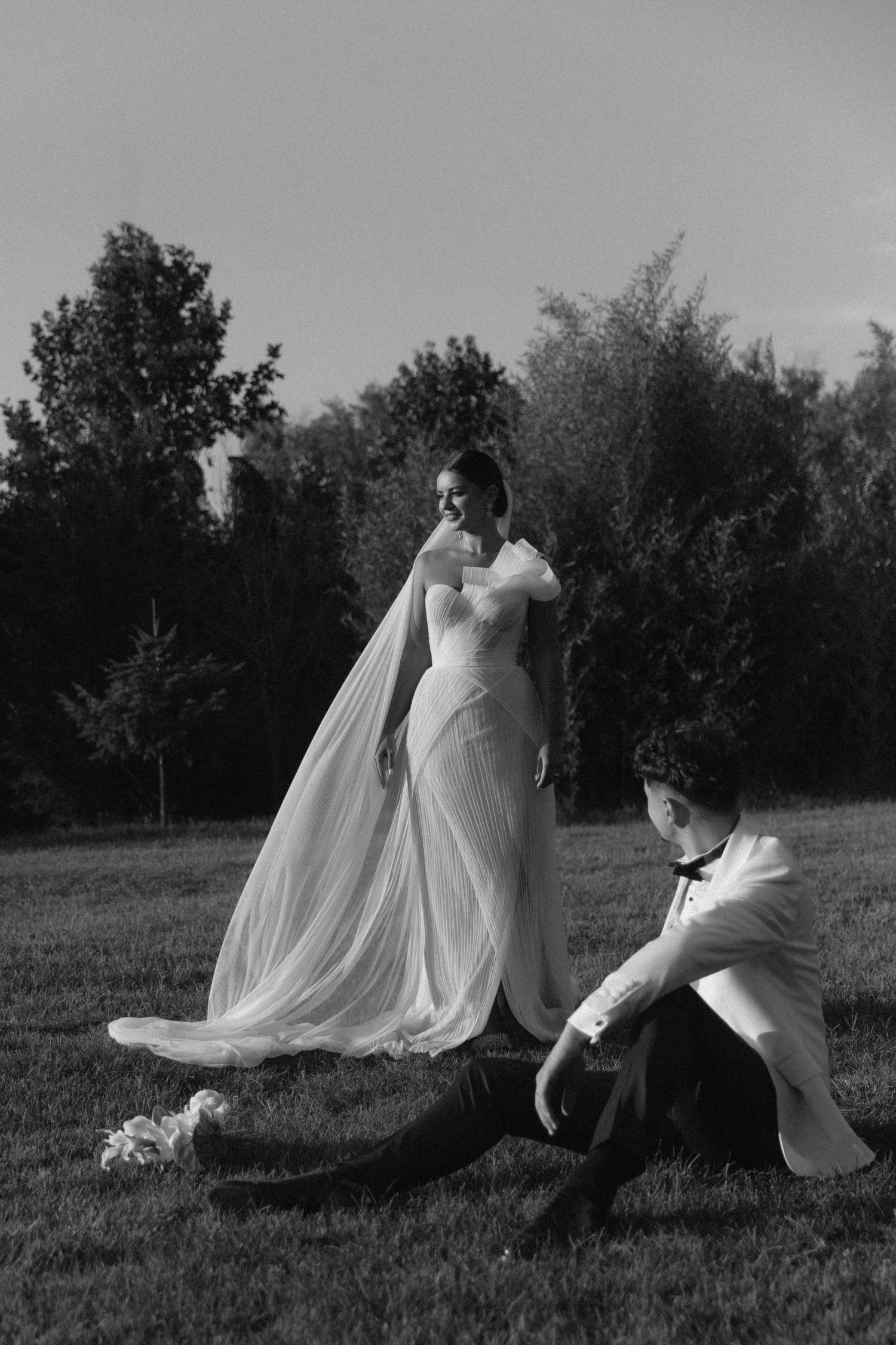 A romantic black and white photo series showing a couple in wedding attire dancing gracefully in a meadow.