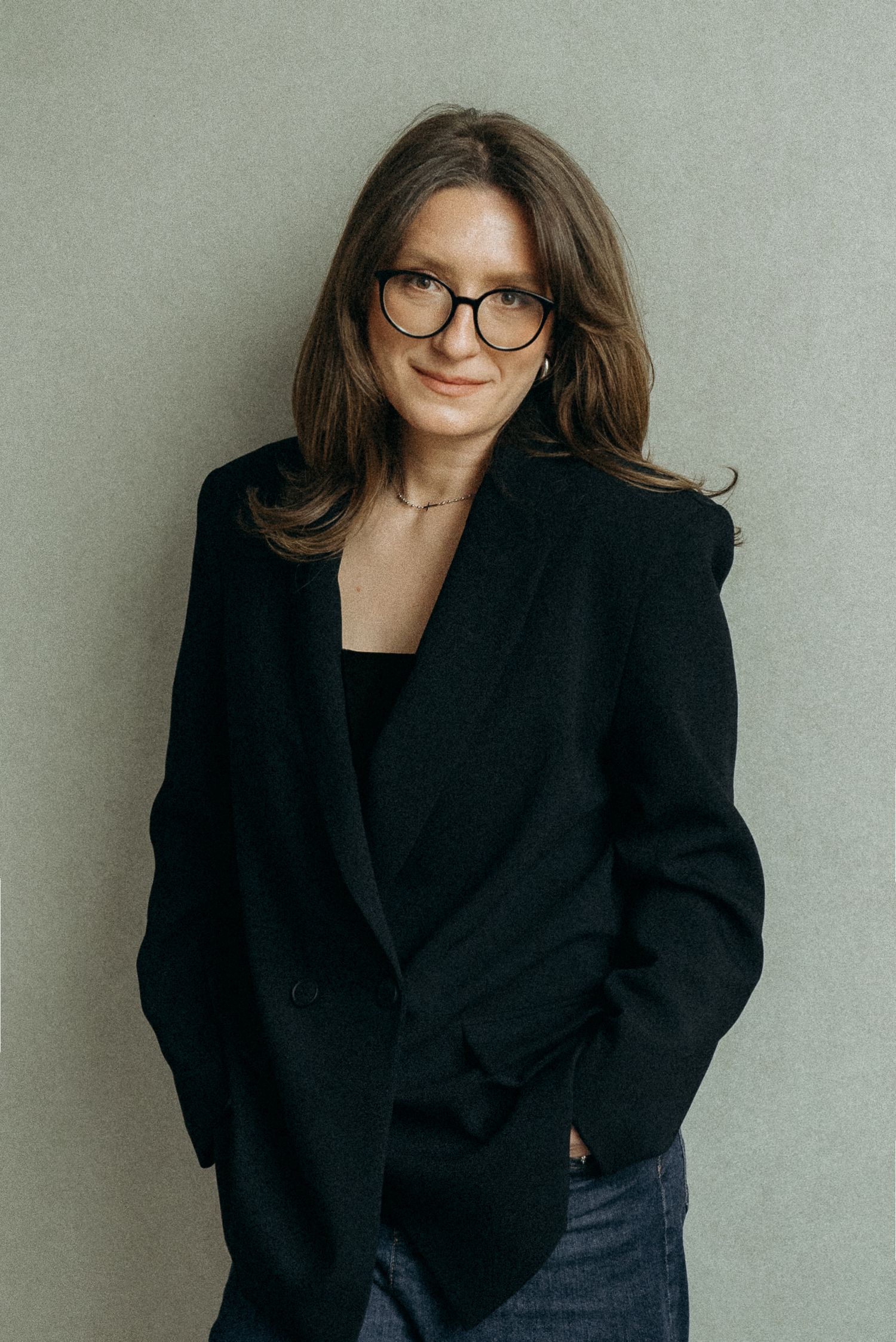 Professional studio portraits showing a person in a black blazer and glasses against a light gray background.