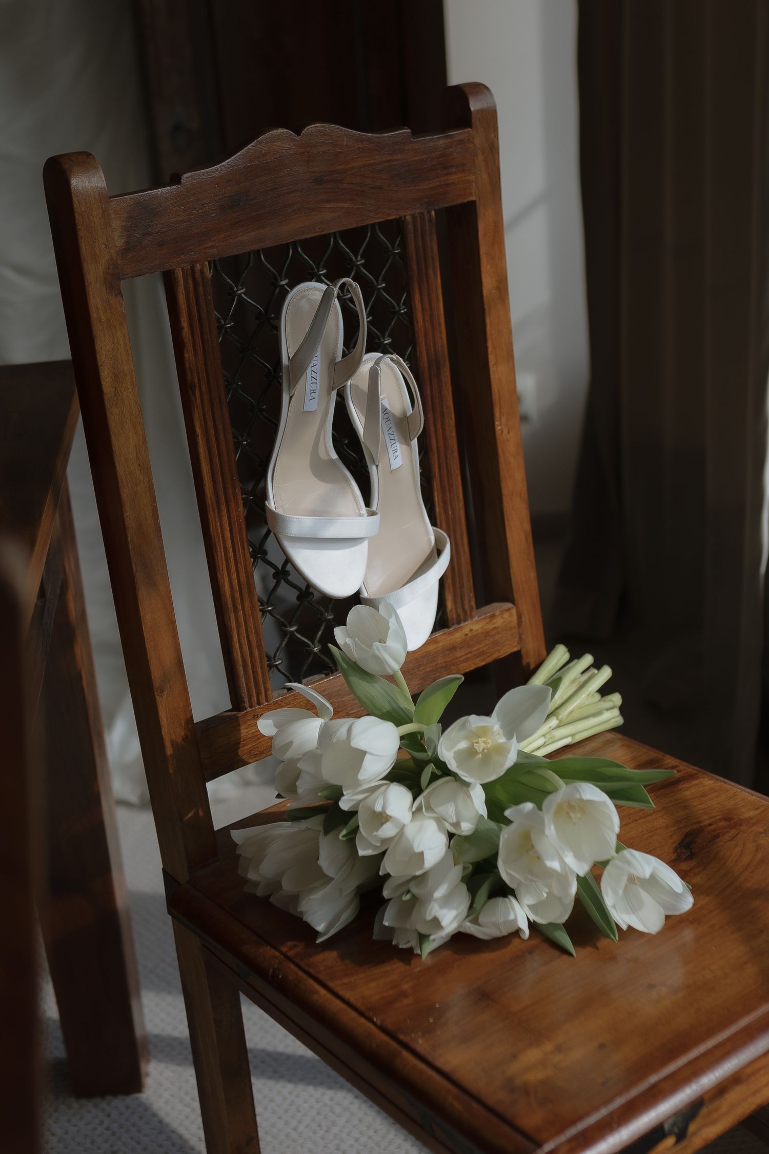 A collection of white tulips resting on a wooden chair shown from different angles in multiple similar photos.