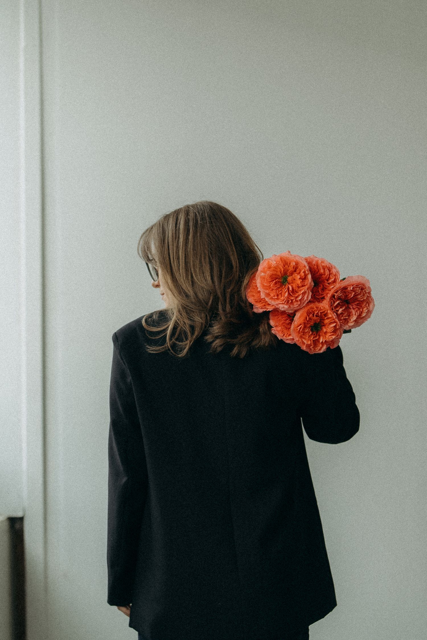 A person in black clothing with vibrant orange poppies on their shoulder shown in a triptych composition.