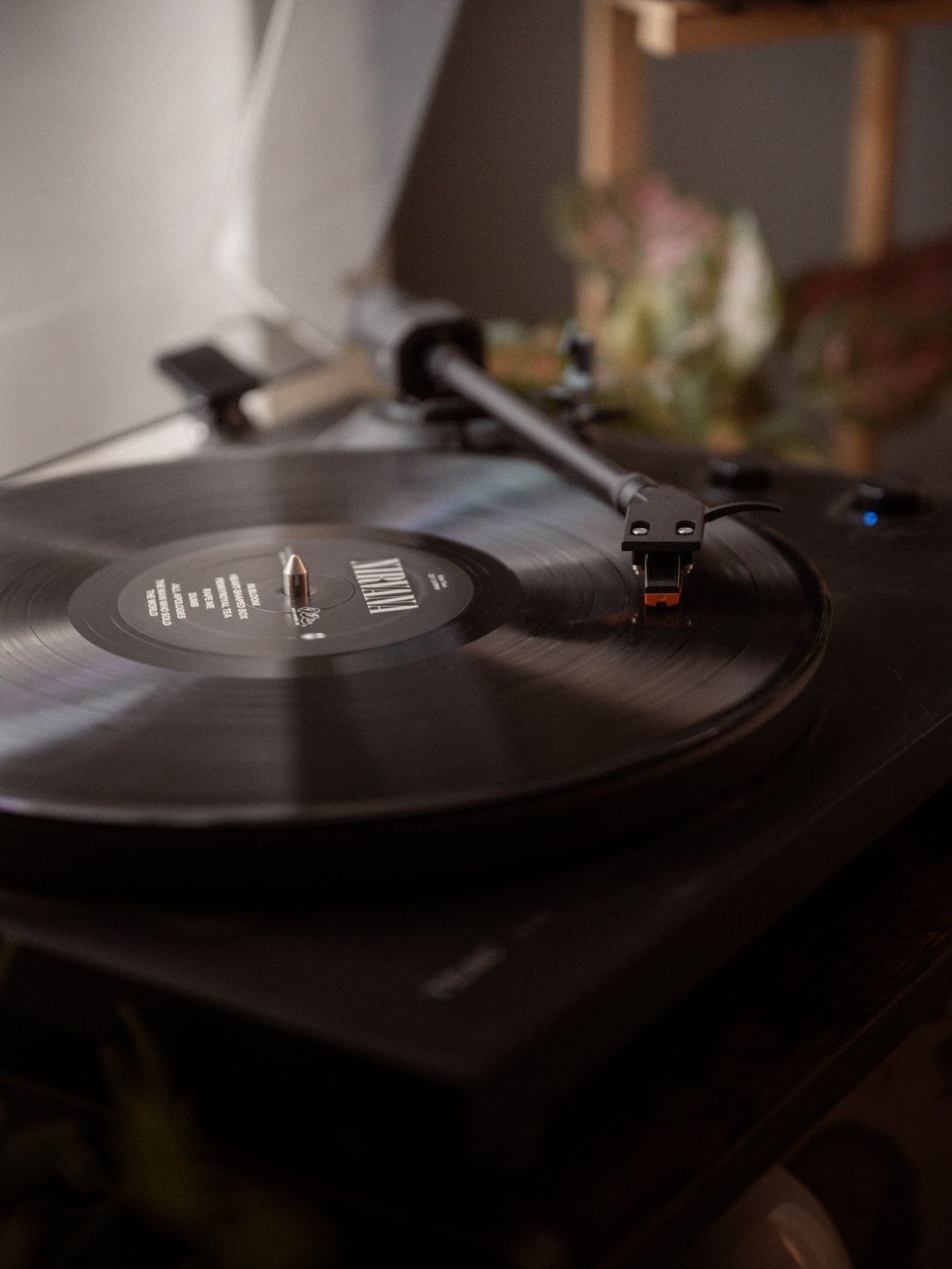 A vinyl record playing on a turntable in moody lighting.