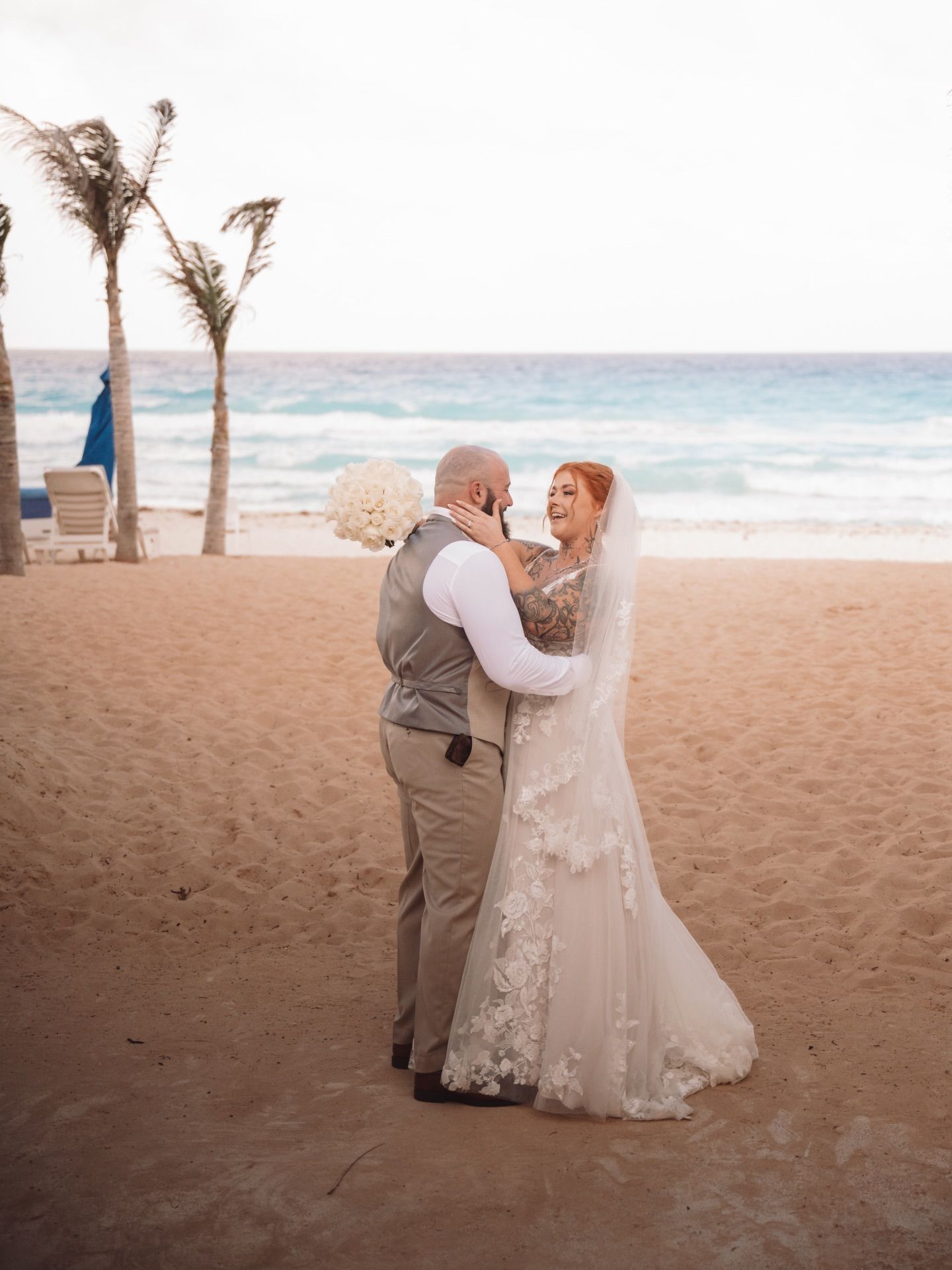 A couple shares an intimate moment during their beach wedding ceremony at sunset.