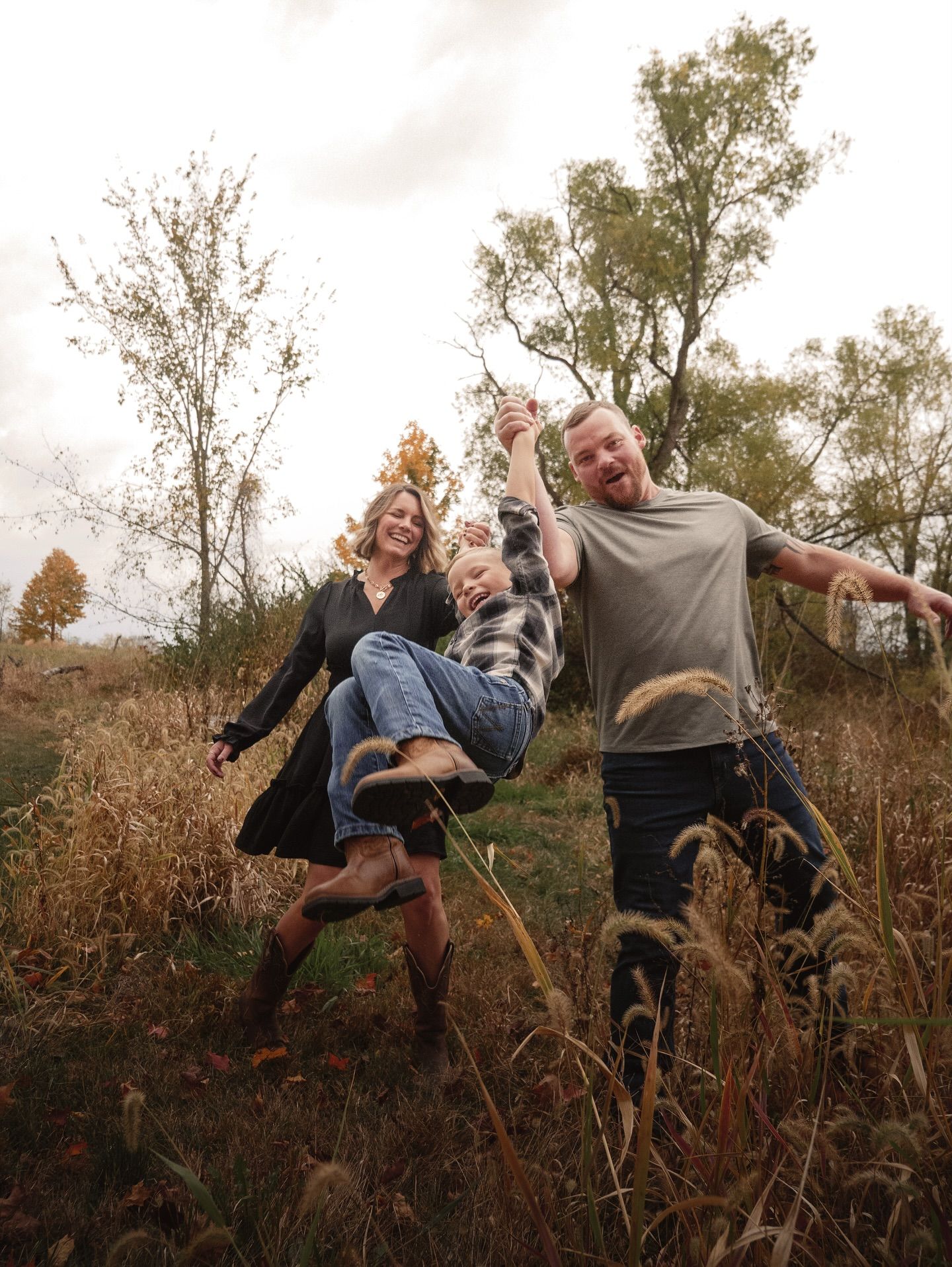 Playful scene of people being lifted and falling backwards in tall grass.