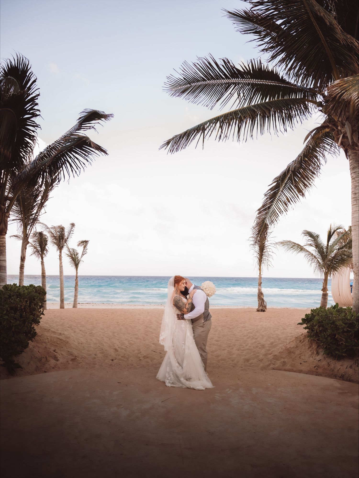 A romantic beach wedding scene with palm trees swaying in the breeze at sunset.
