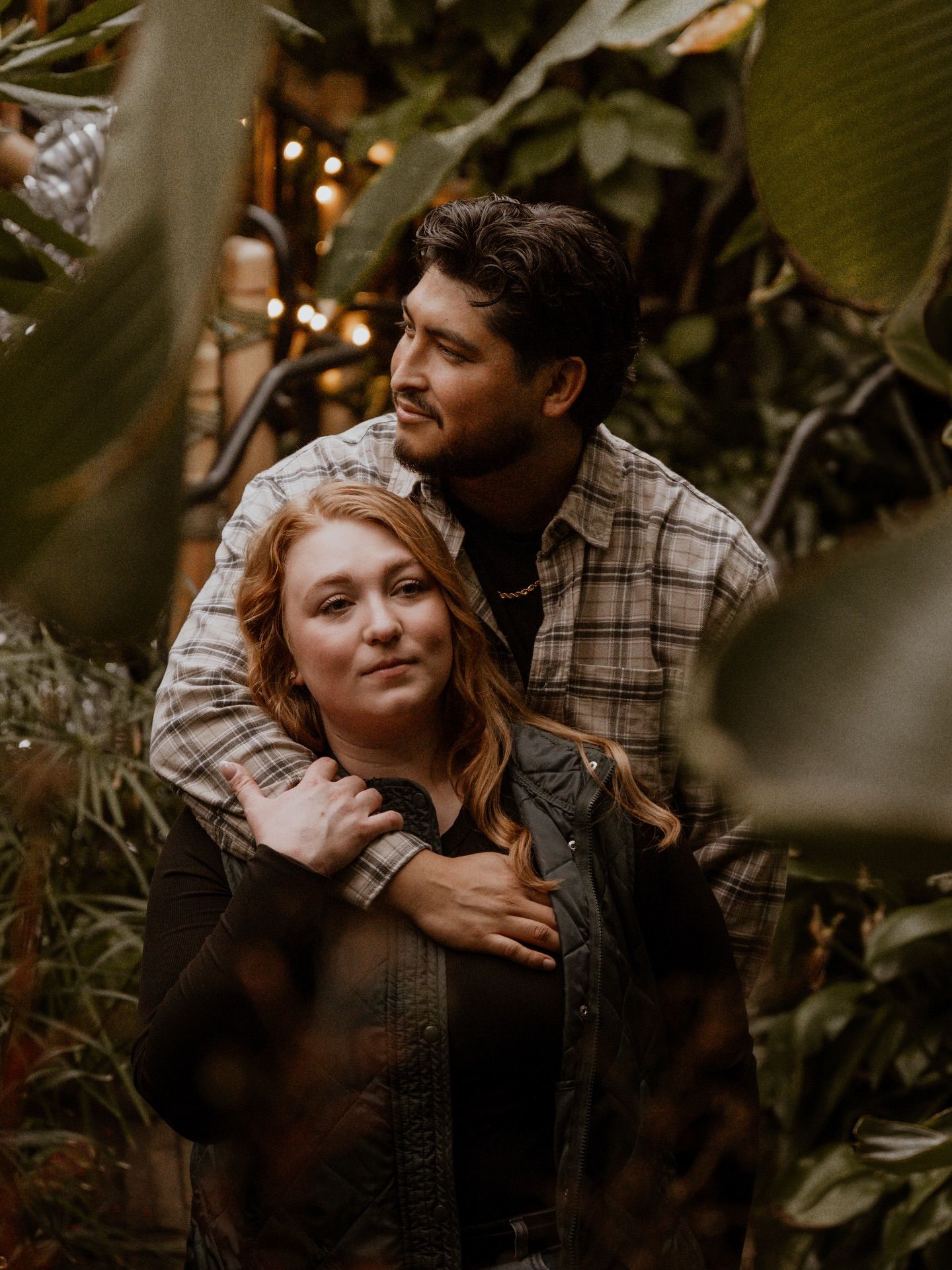 Romantic couple embracing in a lush garden setting with warm ambient lighting.
