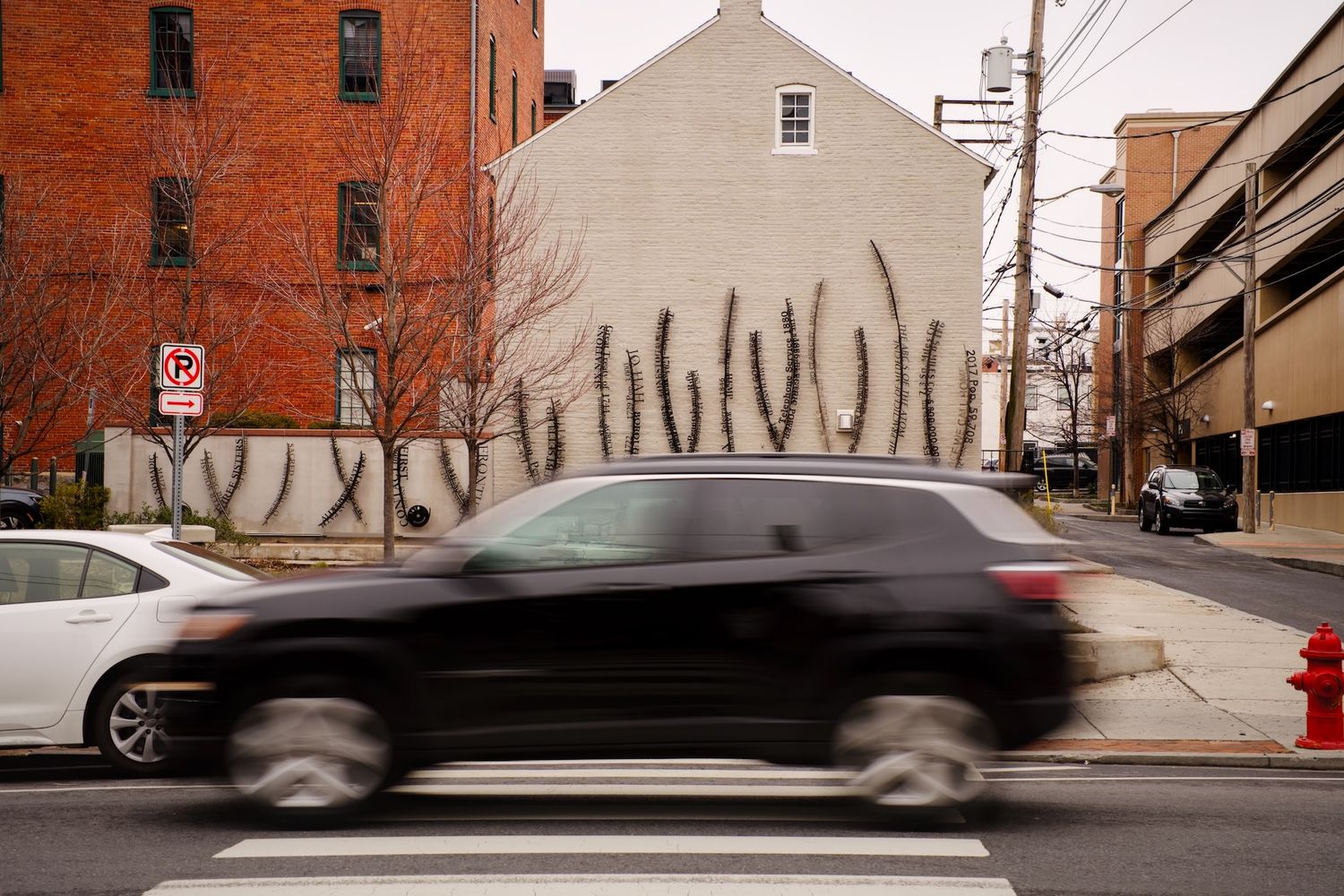 Blurry car passes by art installation on a house in Lancaster.
