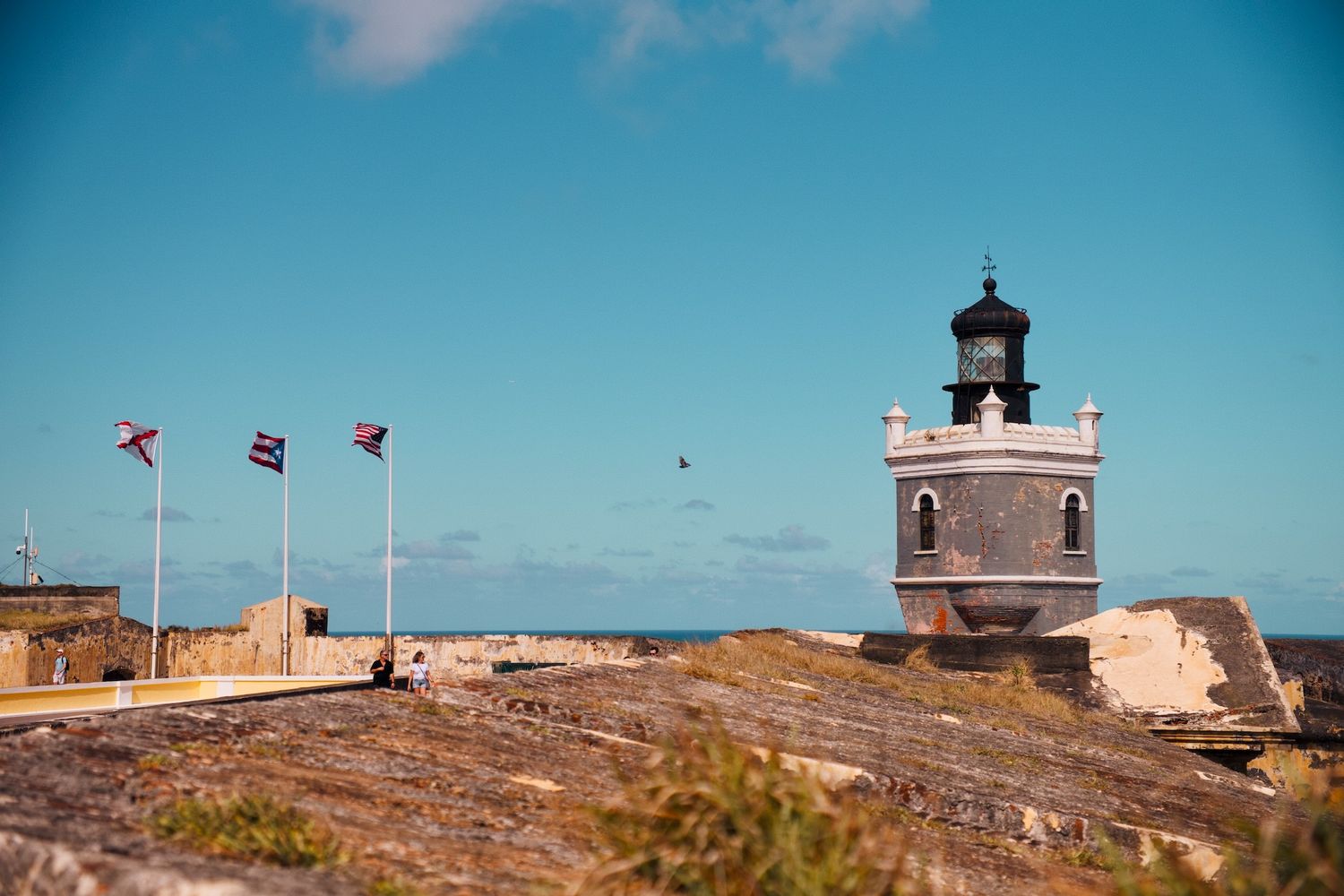 A lighthouse and flags at a San Juan fort.