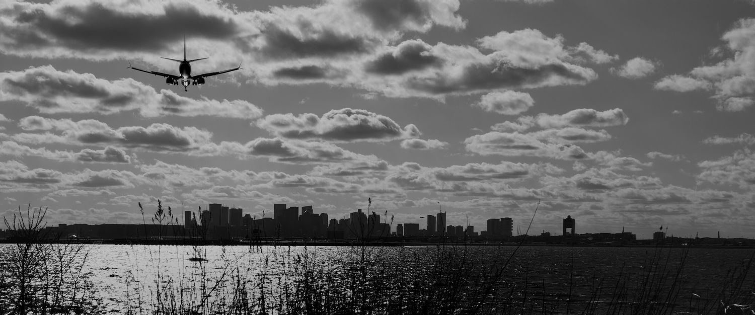 Boston skyline with plane landing at Logan Airport.